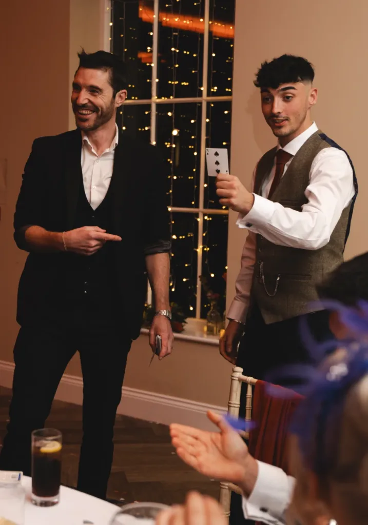 A group of people at a dinner party with a magician providing wedding entertainment ideas.