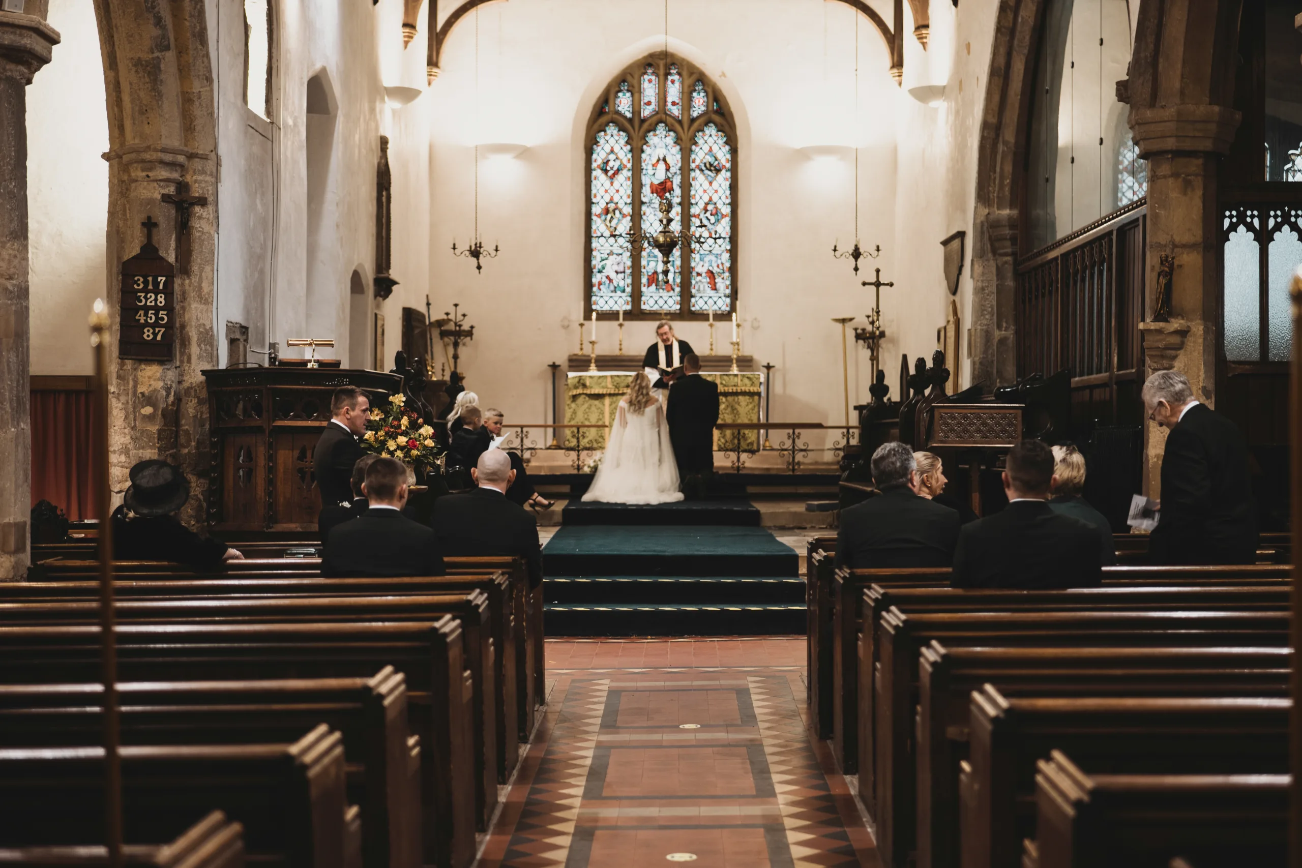 A bride and groom standing in the pews of Hirst Priory church.