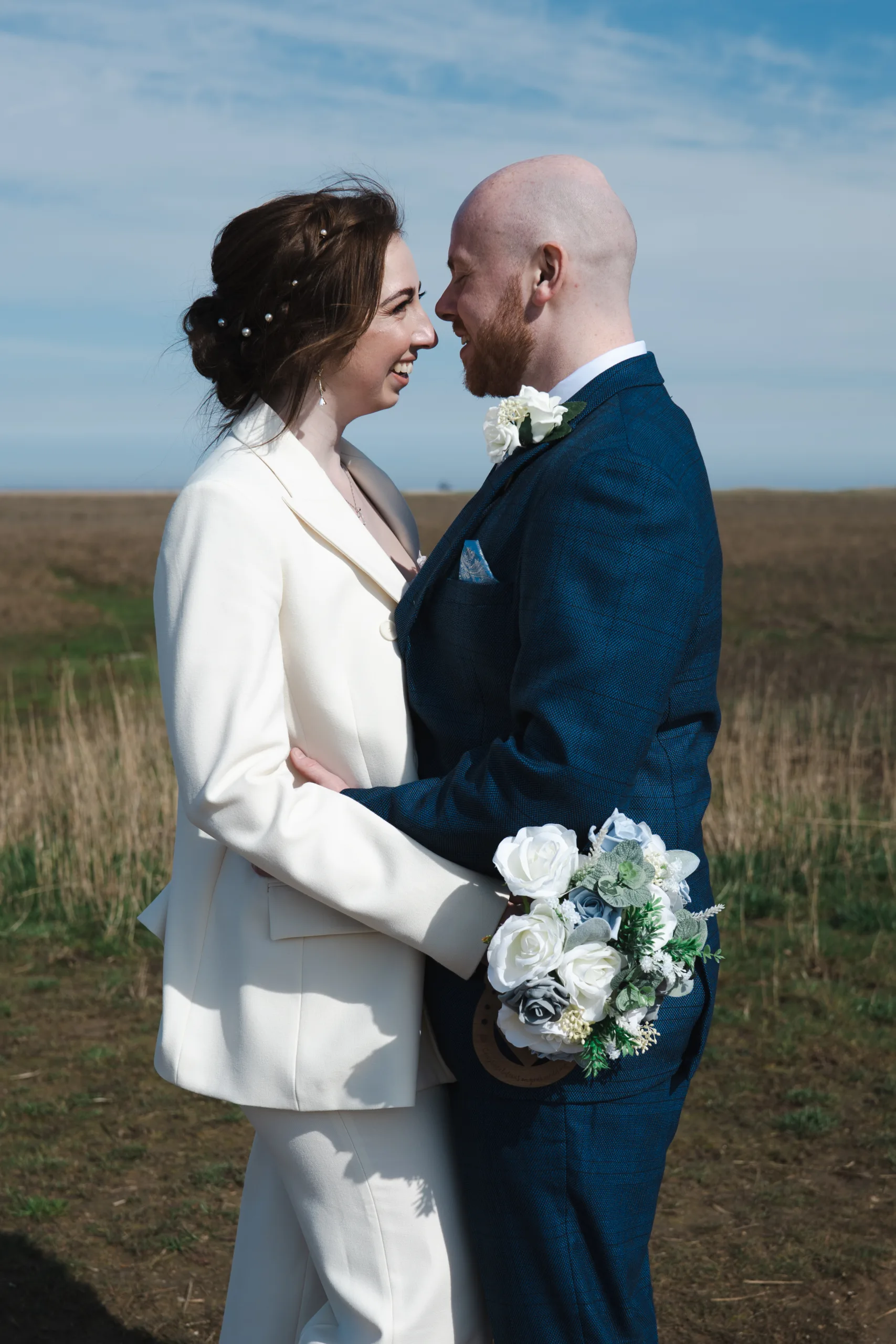 A bride and groom embracing on Cleethorpes beach.