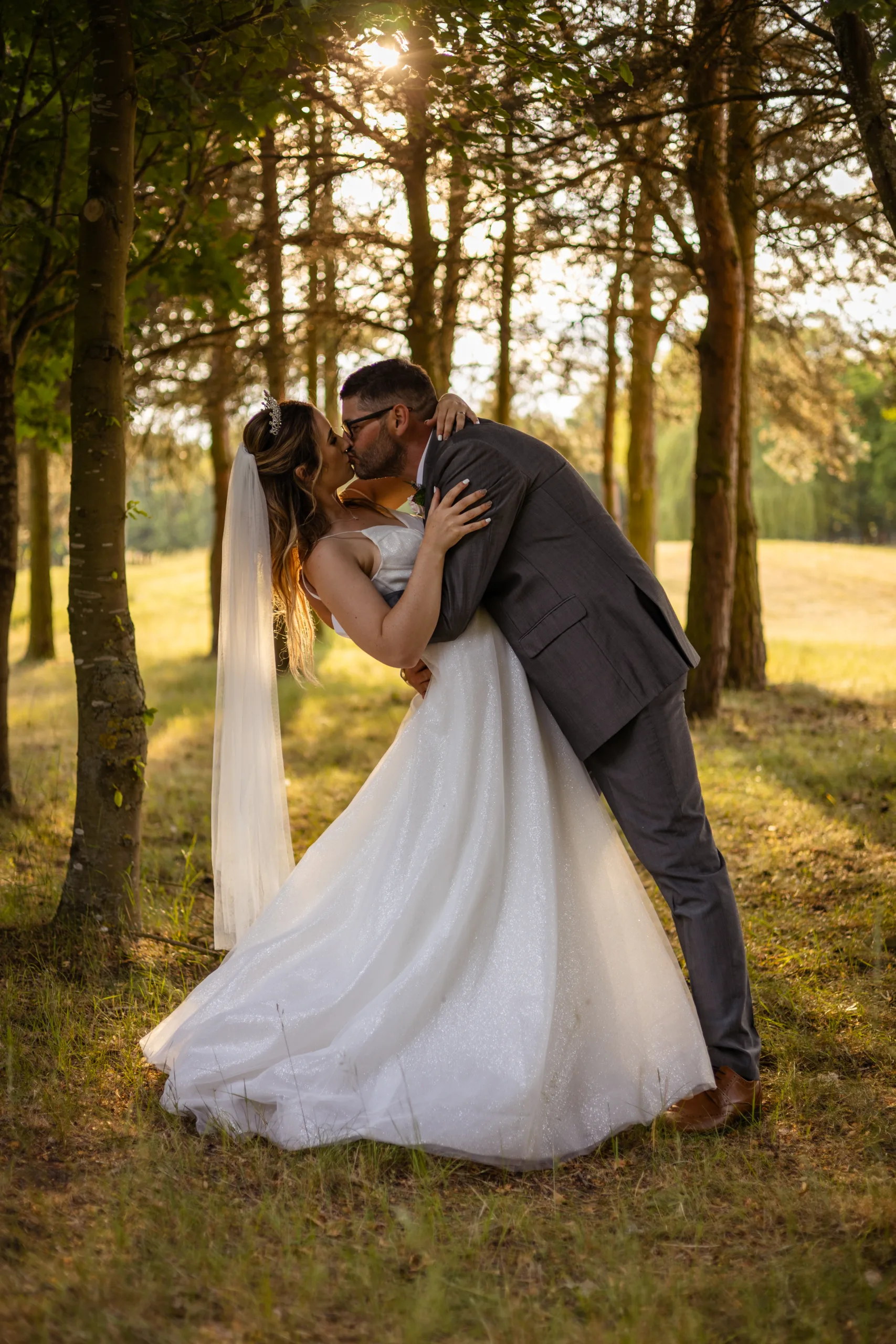 A wedding couple sharing a loving kiss amidst the enchanting scenery of Messingham Grange in Scunthorpe.