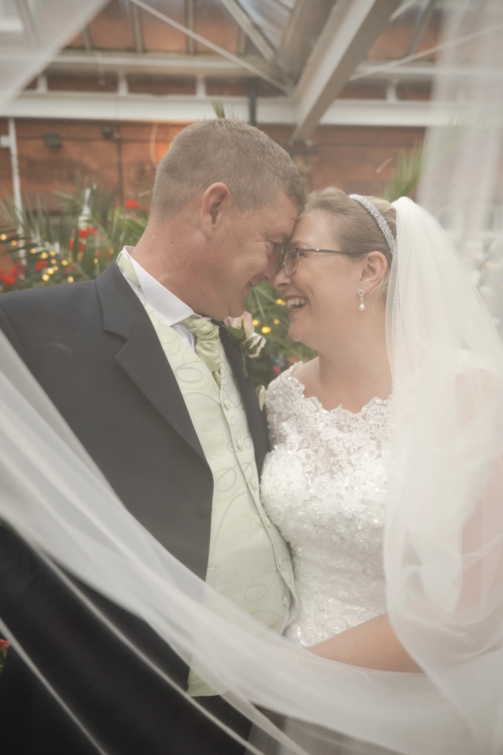 A Sleaford bride and groom embracing under a veil during their rainy wedding at Carre Arms Hotel.