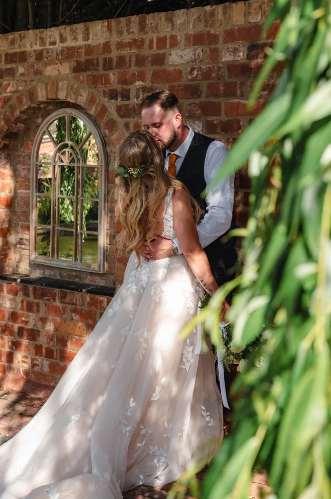 A Stallingborough wedding couple sharing a tender kiss in front of a brick wall.