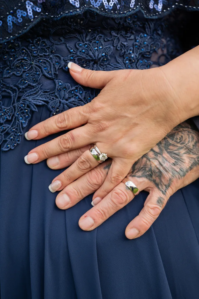 A woman with tattoos on her hands holding a wedding ring at Ross Castle.