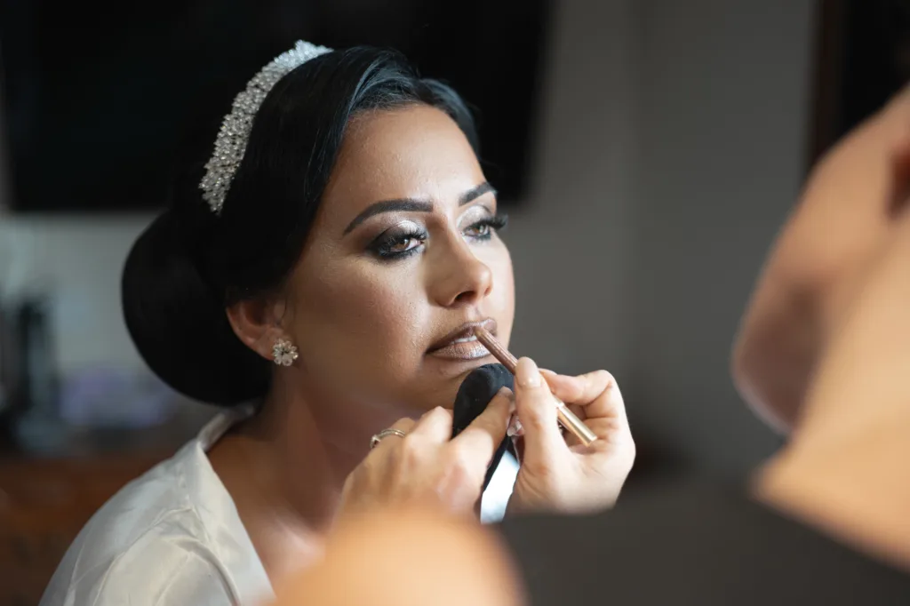 Rebecca getting her makeup done in front of a mirror at the Stallingborough Grange Hotel for her royal wedding with Saul.