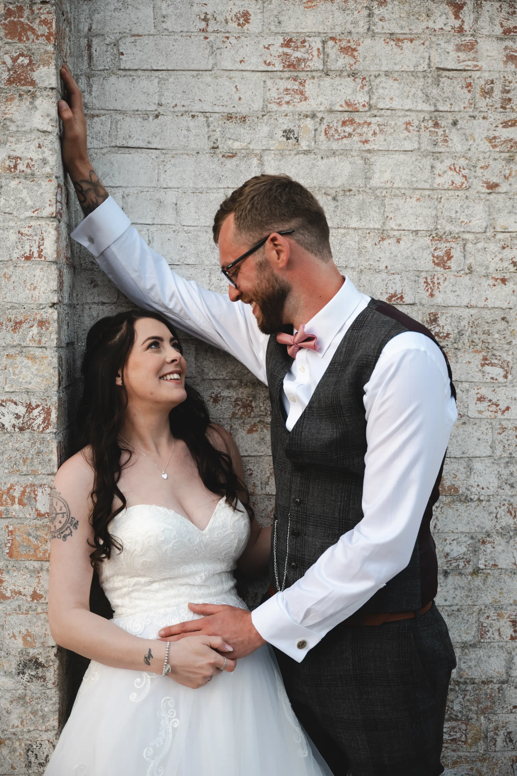 A bride and groom leaning against a brick wall at Hall Farm Hotel.