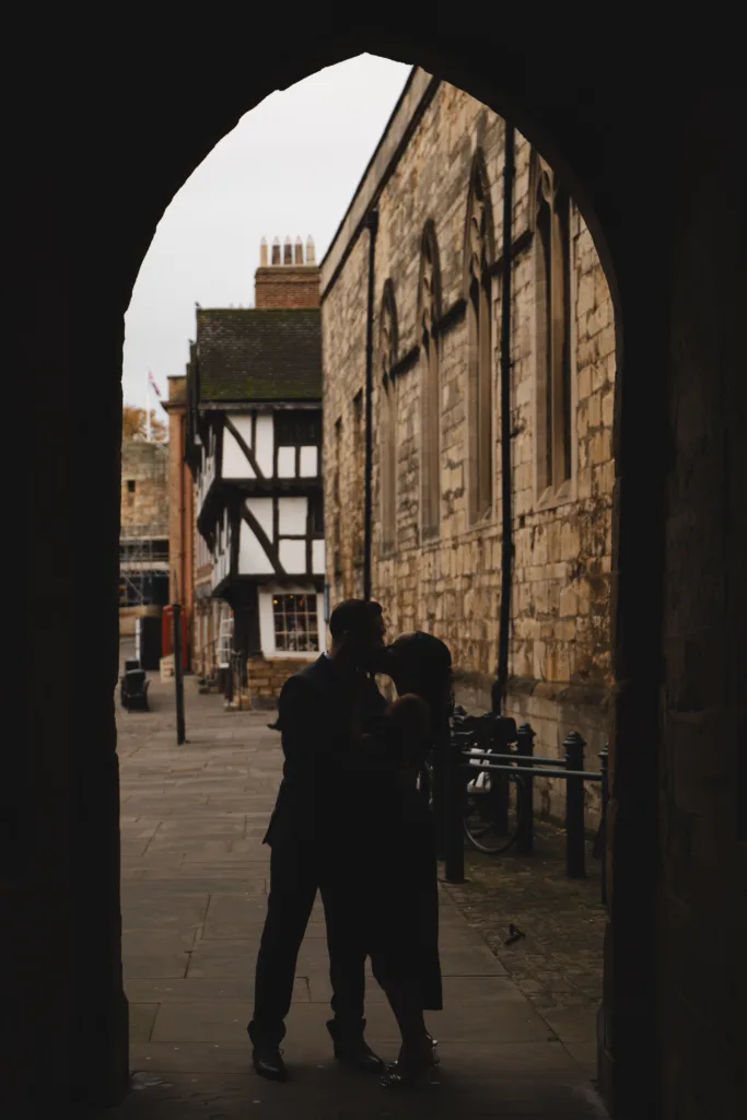 A couple sharing a passionate kiss against the backdrop of an archway in the vibrant city of Lincoln.