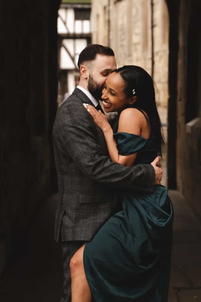 A couple embracing in a Lincoln alleyway during their engagement session.