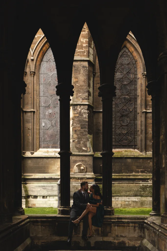 A couple sits on the steps of a church during their engagement session.
