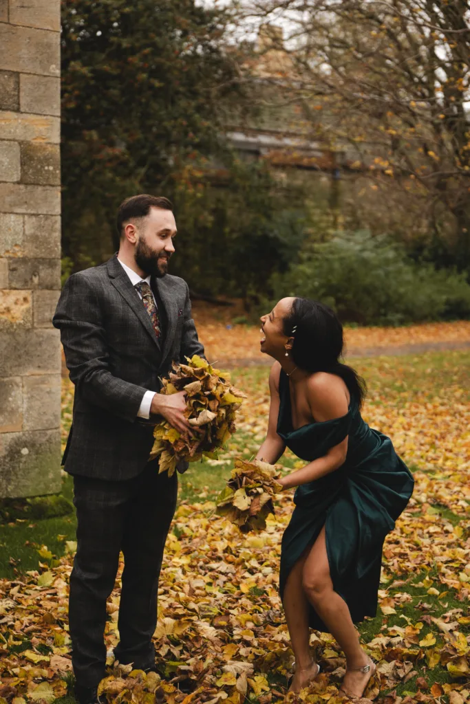 In this Lincoln engagement session, a man and woman are captured holding leaves in front of a building, creating an intimate moment for street photography enthusiasts.