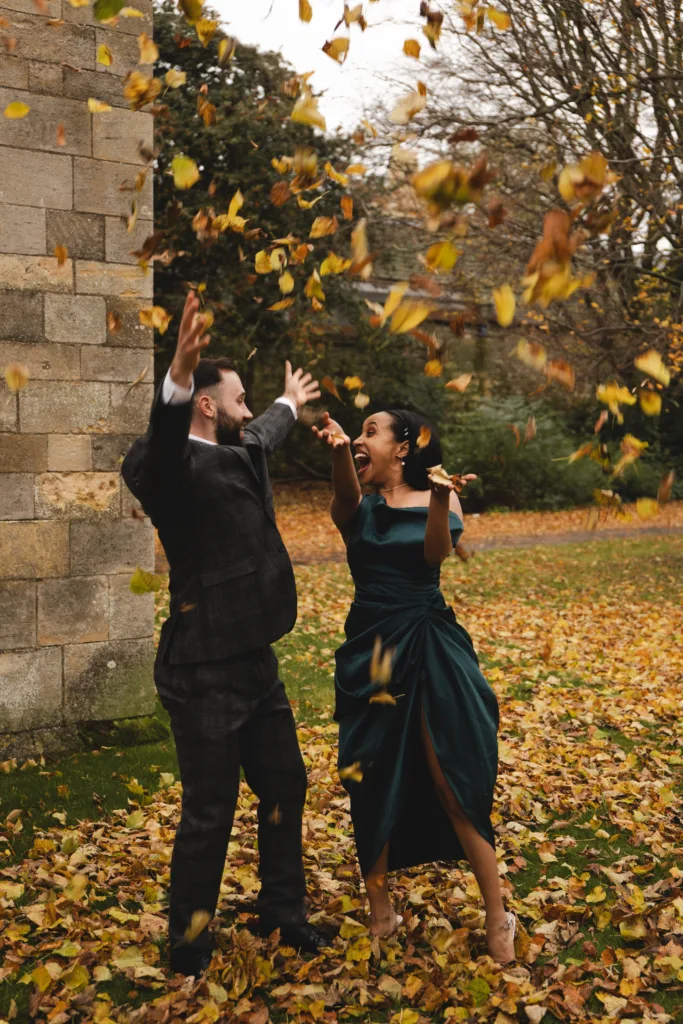 In this engagement session, the couple joyfully throw leaves in front of a majestic castle.