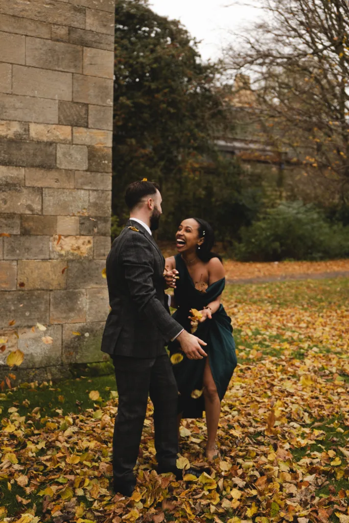 An engaged couple twirling and dancing in the autumn leaves on a Lincoln street, captured in breathtaking street photography.