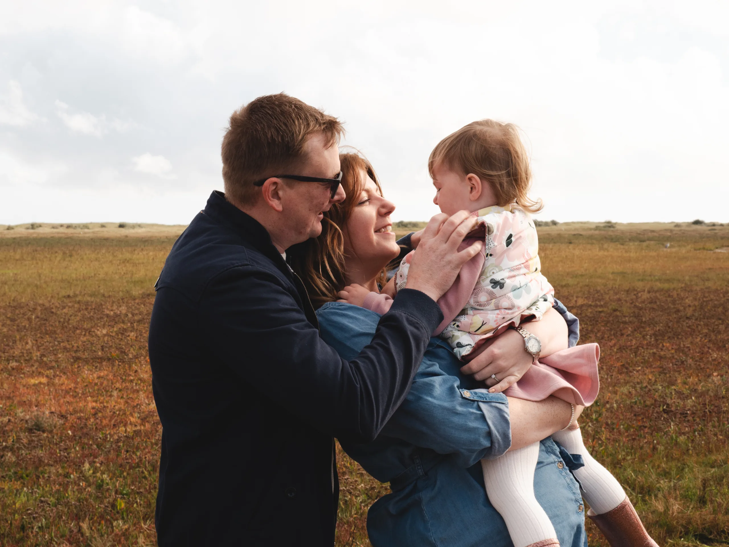 Mother, father and young daughter hugging at Cleethorpes Boating Lake Beach