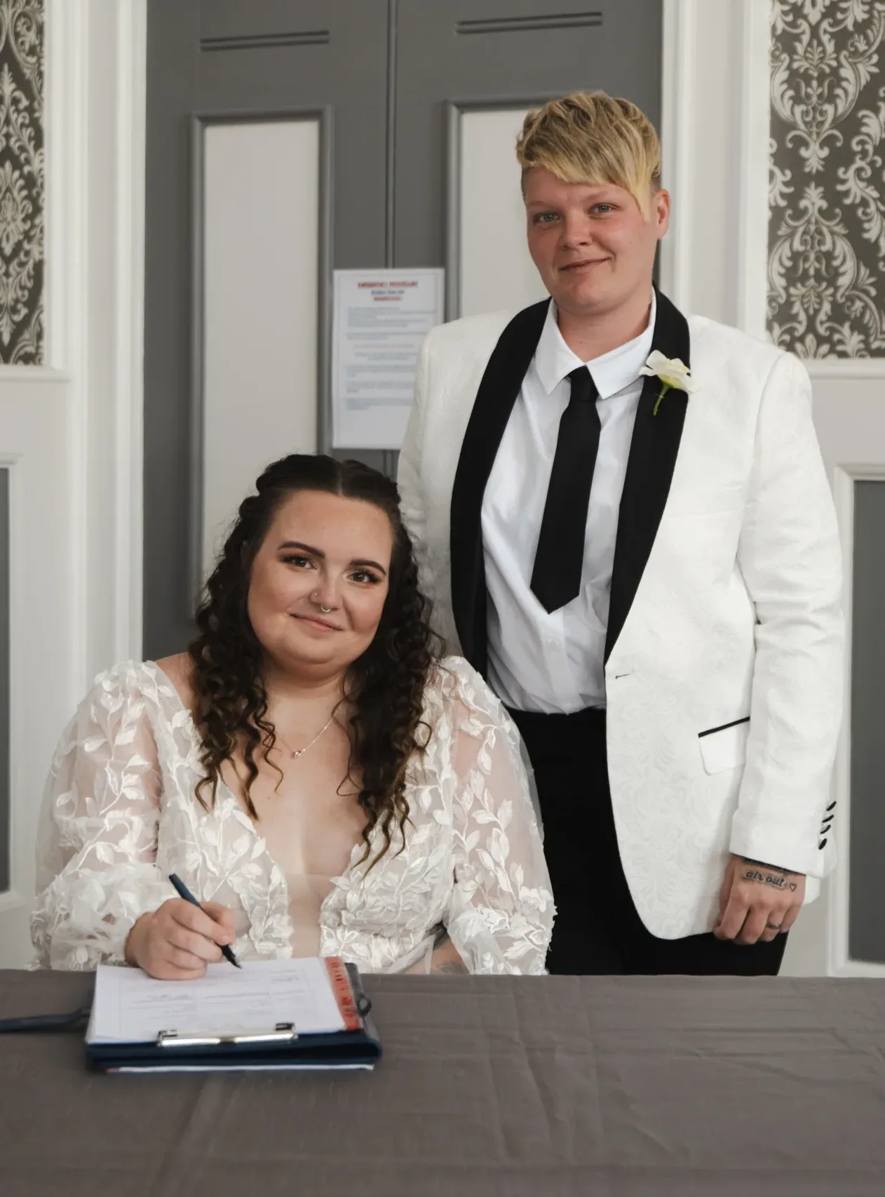 A wedding couple signing their wedding vows at a beautifully decorated table.