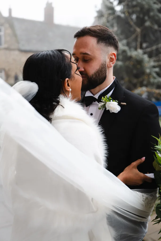 A breathtaking moment captured of a bride and groom sharing an intimate kiss under a veil, symbolizing love and new beginnings.