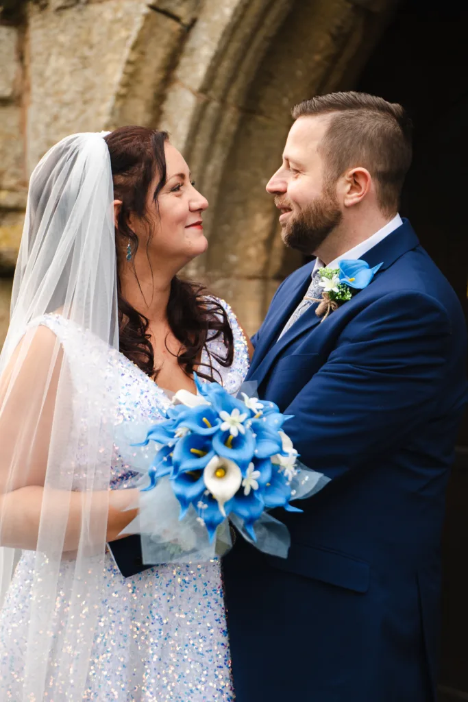 Bride and groom smiling at each other outside of East Drayton church.