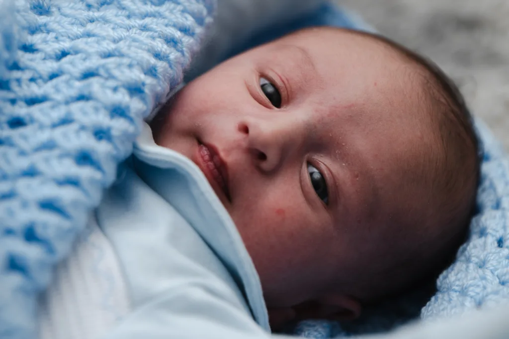 A newborn baby is wrapped in a blue blanket.