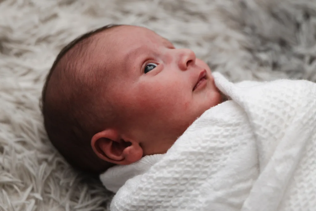 A newborn baby boy is wrapped in a white blanket.