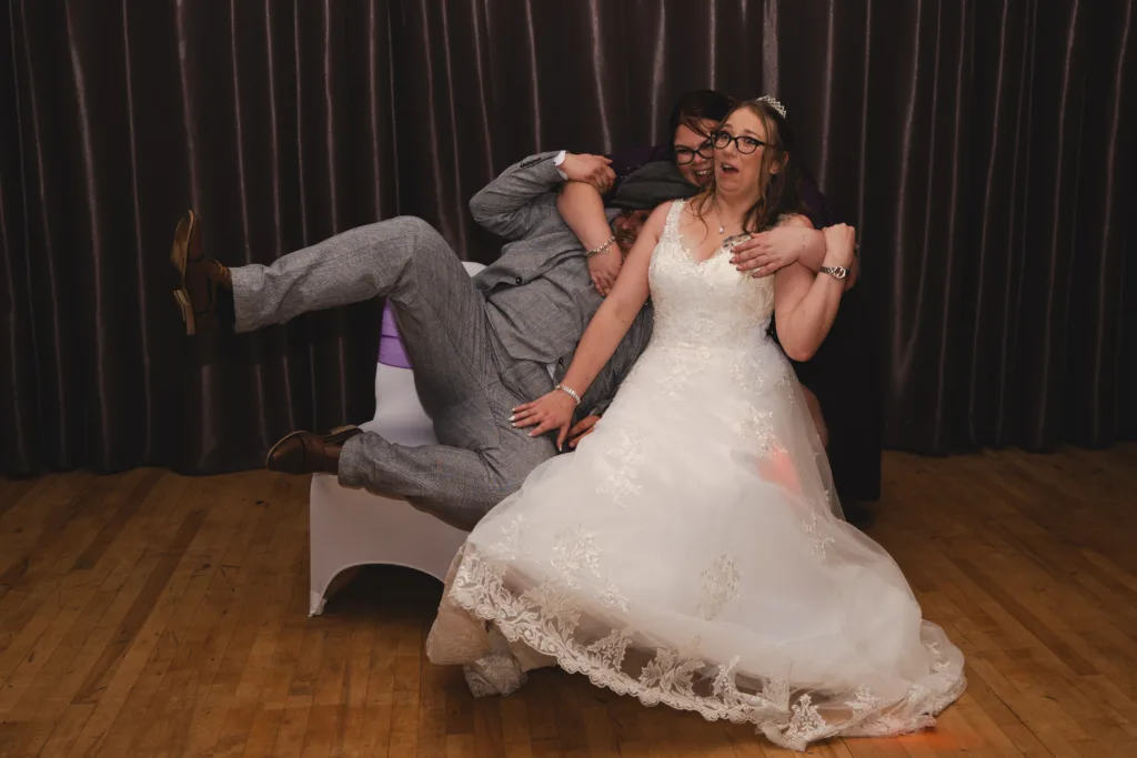 A bride and groom are having a good time on the dance floor while a photo is being taken.