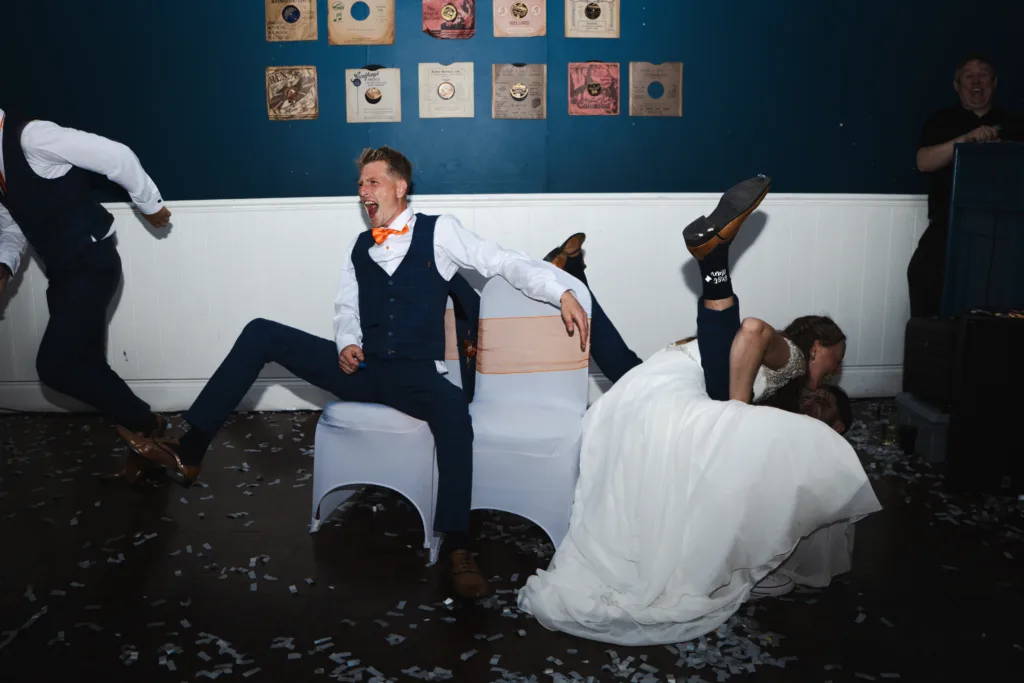 A bride and groom dancing in a room with confetti, captured in a joyful photo moment.