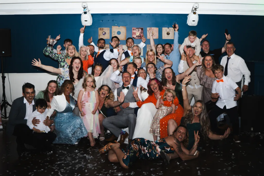 A group of people posing for a roulette-themed photo at a wedding.