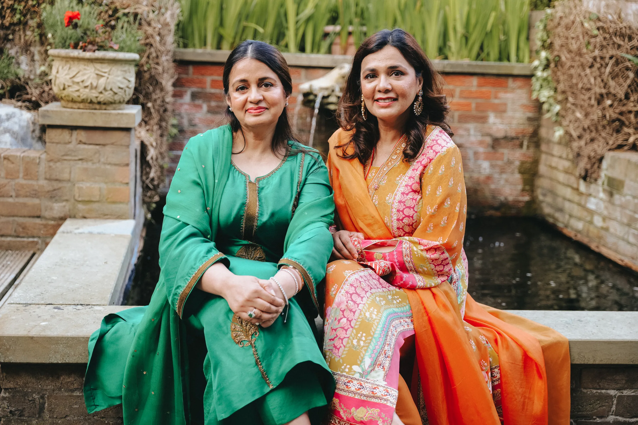 Two Indian women posing in front of a fountain at a wedding in Lincolnshire.