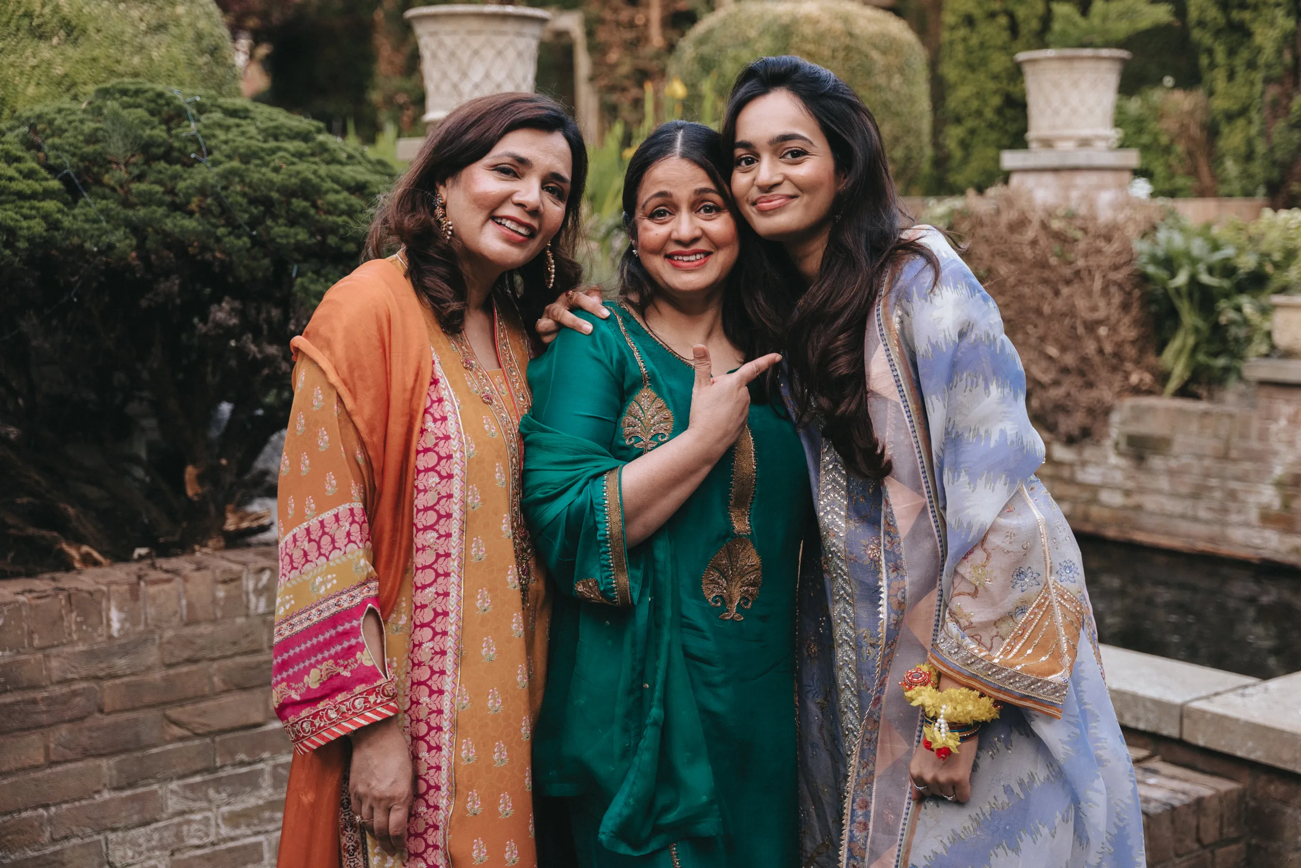 Three Indian women posing for a photo in a garden, captured by a photographer in Lincolnshire.