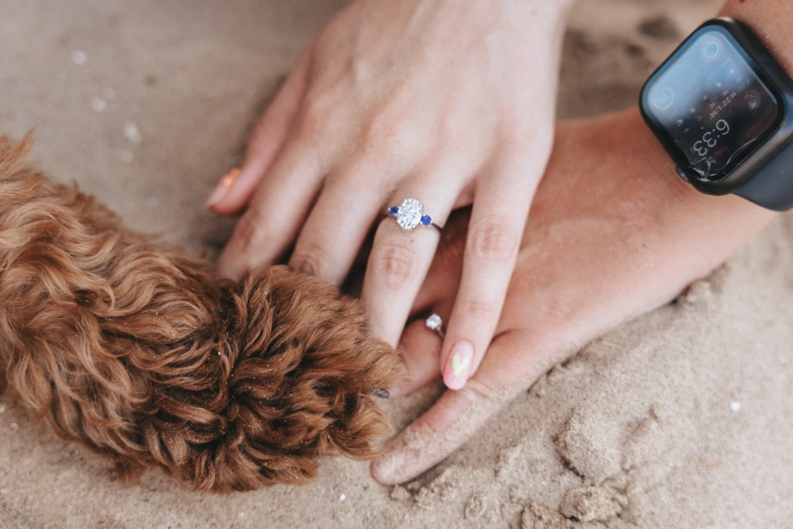 A woman with a wedding ring on her finger poses with a dog in the sand for a photography shoot in Yorkshire.
