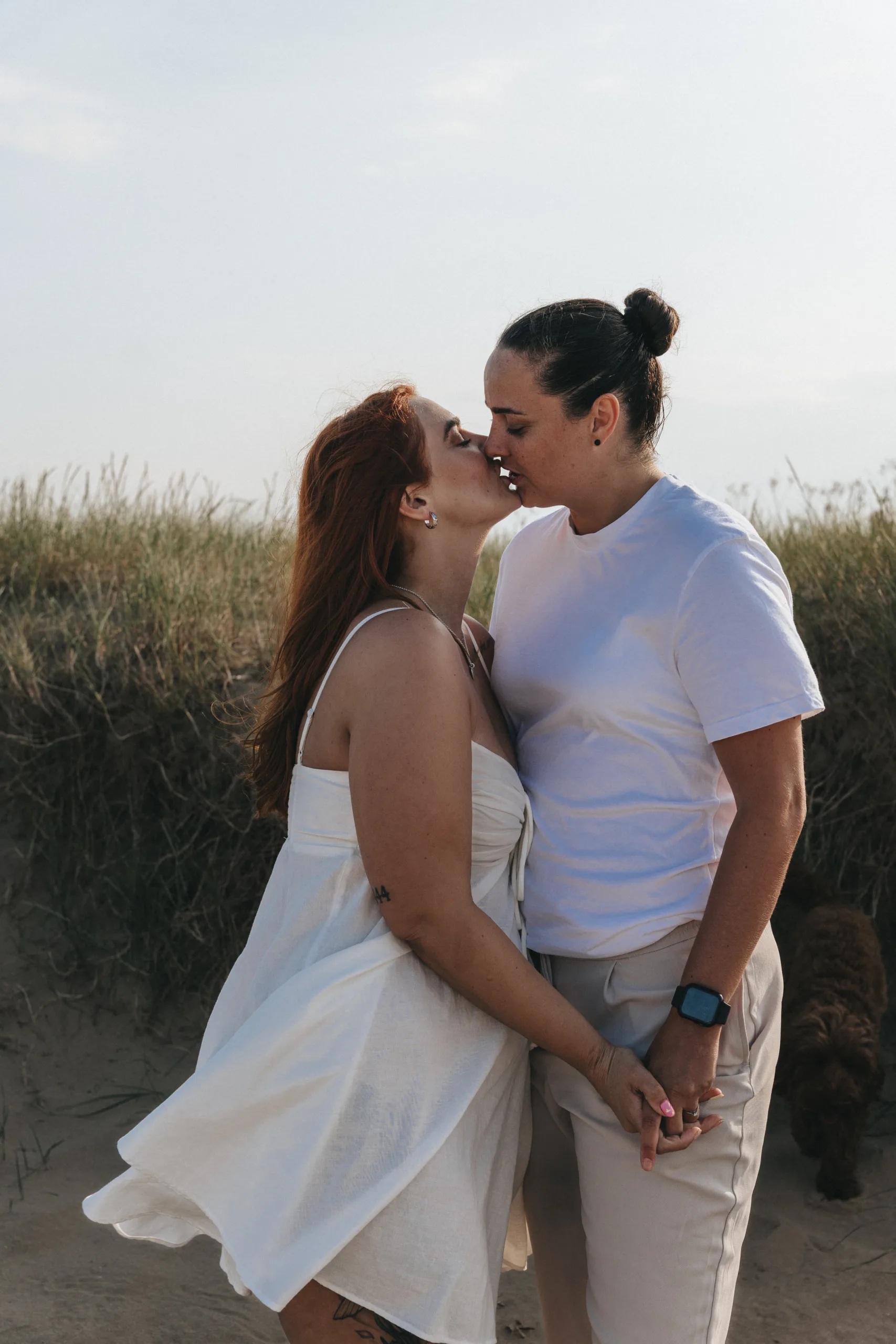 Two women sharing a kiss on the sandy shoreline of a beach in Yorkshire.