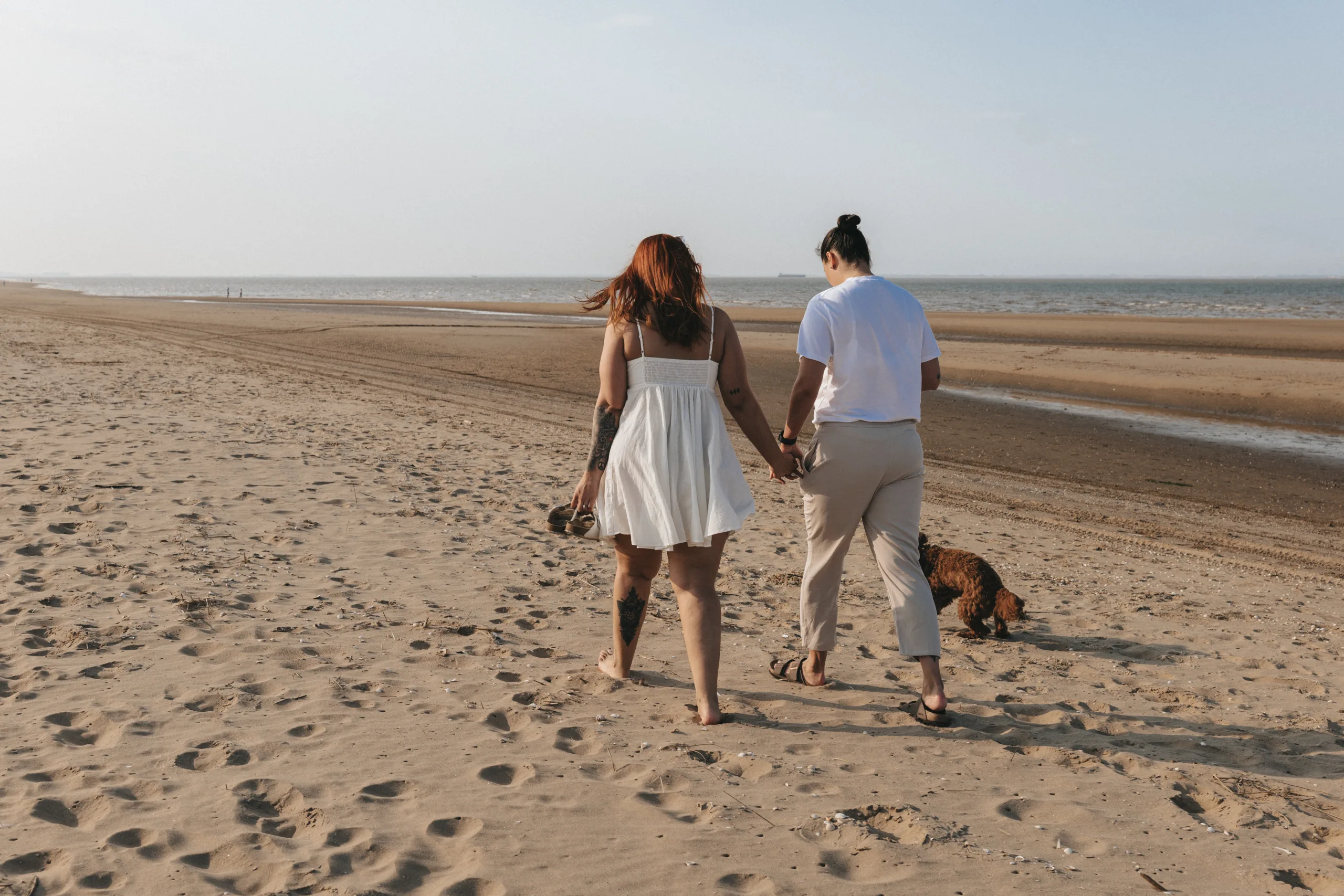 A couple walking on the beach with their dog in Yorkshire.