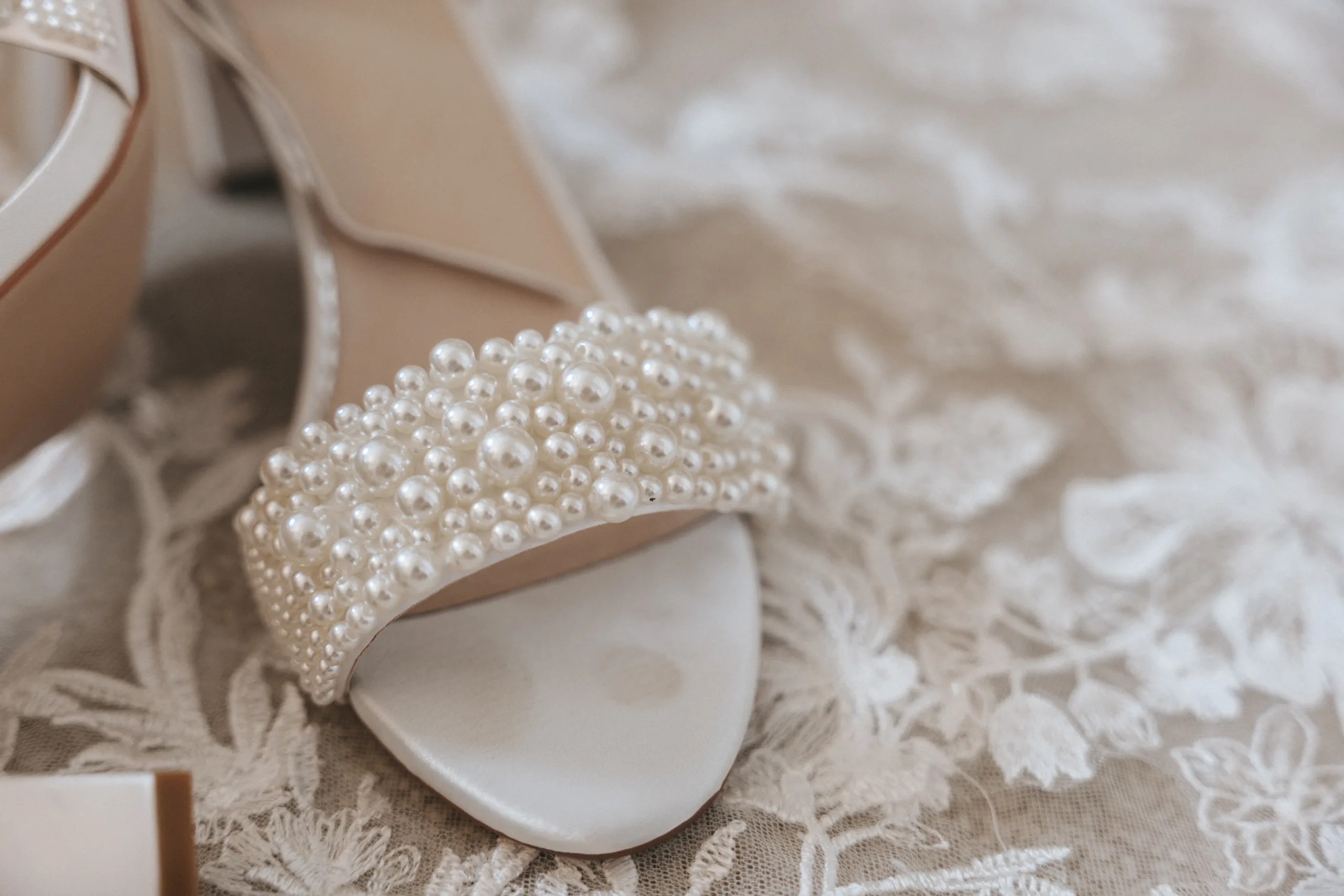 A pair of white wedding shoes adorned with pearls, perfect for a wedding day photoshoot.