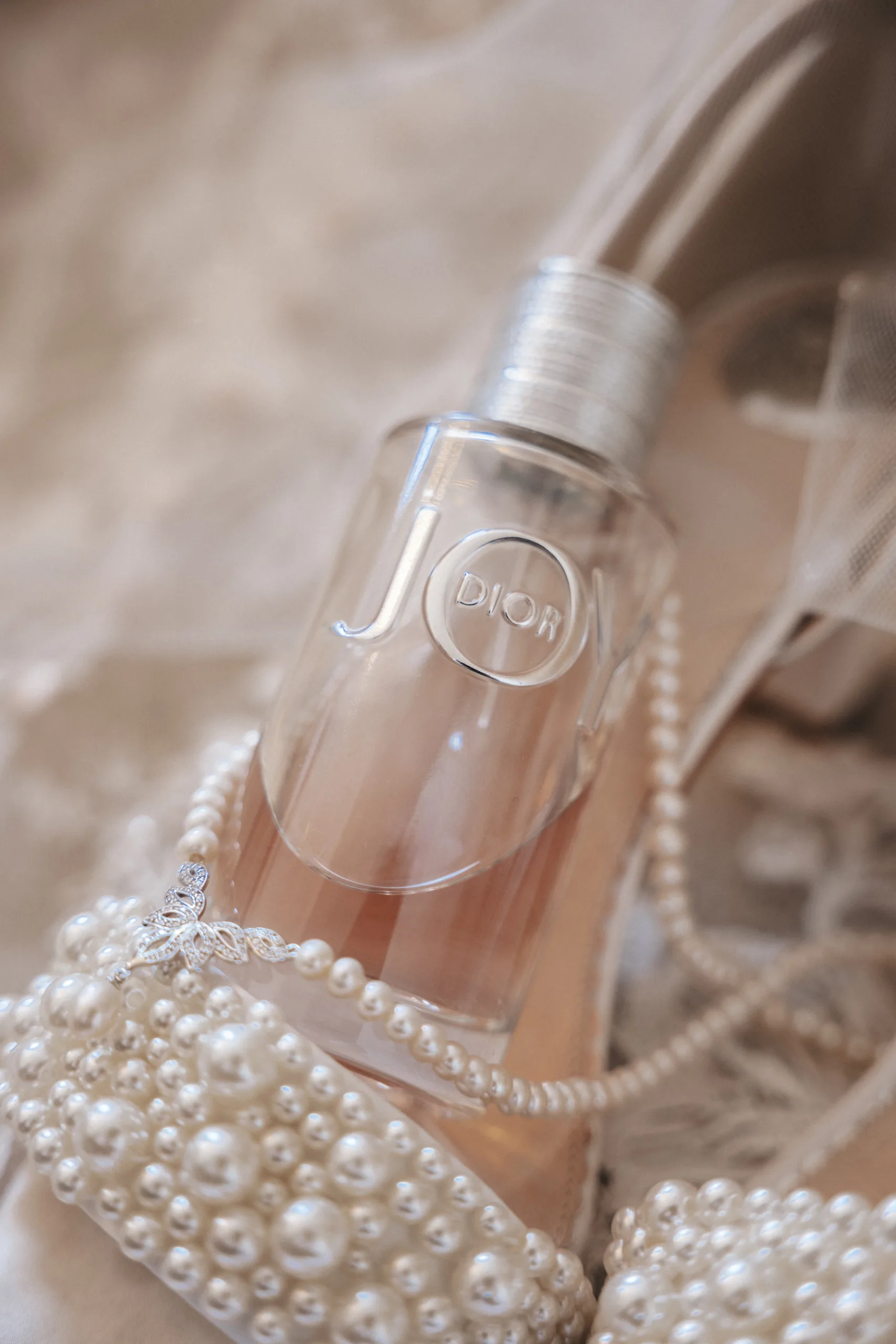 A pair of wedding shoes adorned with elegant pearls and a bottle of exquisite perfume designed for your special day.