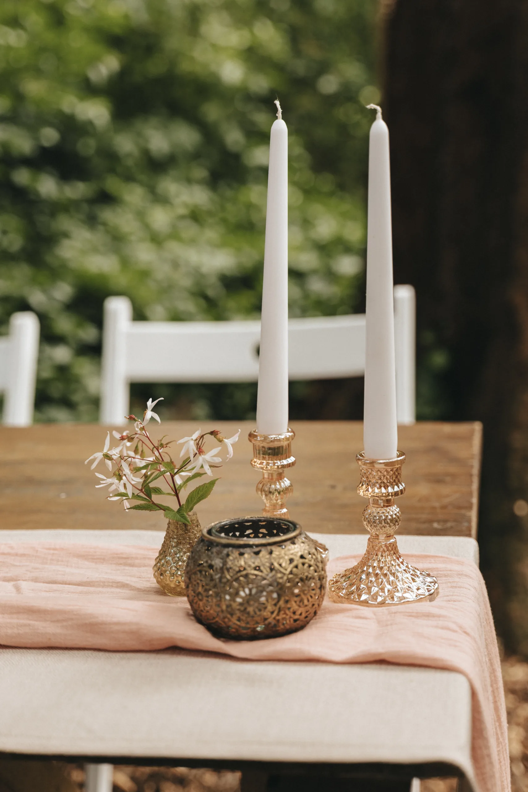 Two candles on a table in the woods, perfect for a photography shoot.