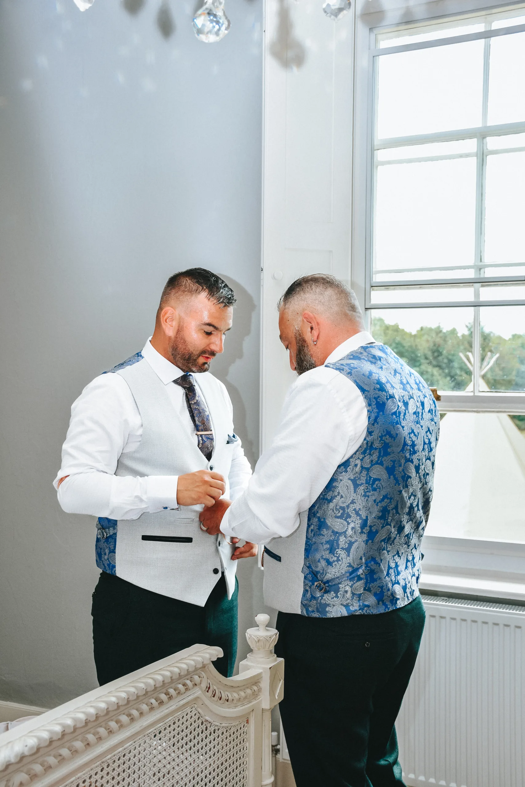 Two grooms getting ready in front of a mirror for their wedding in Lincolnshire.