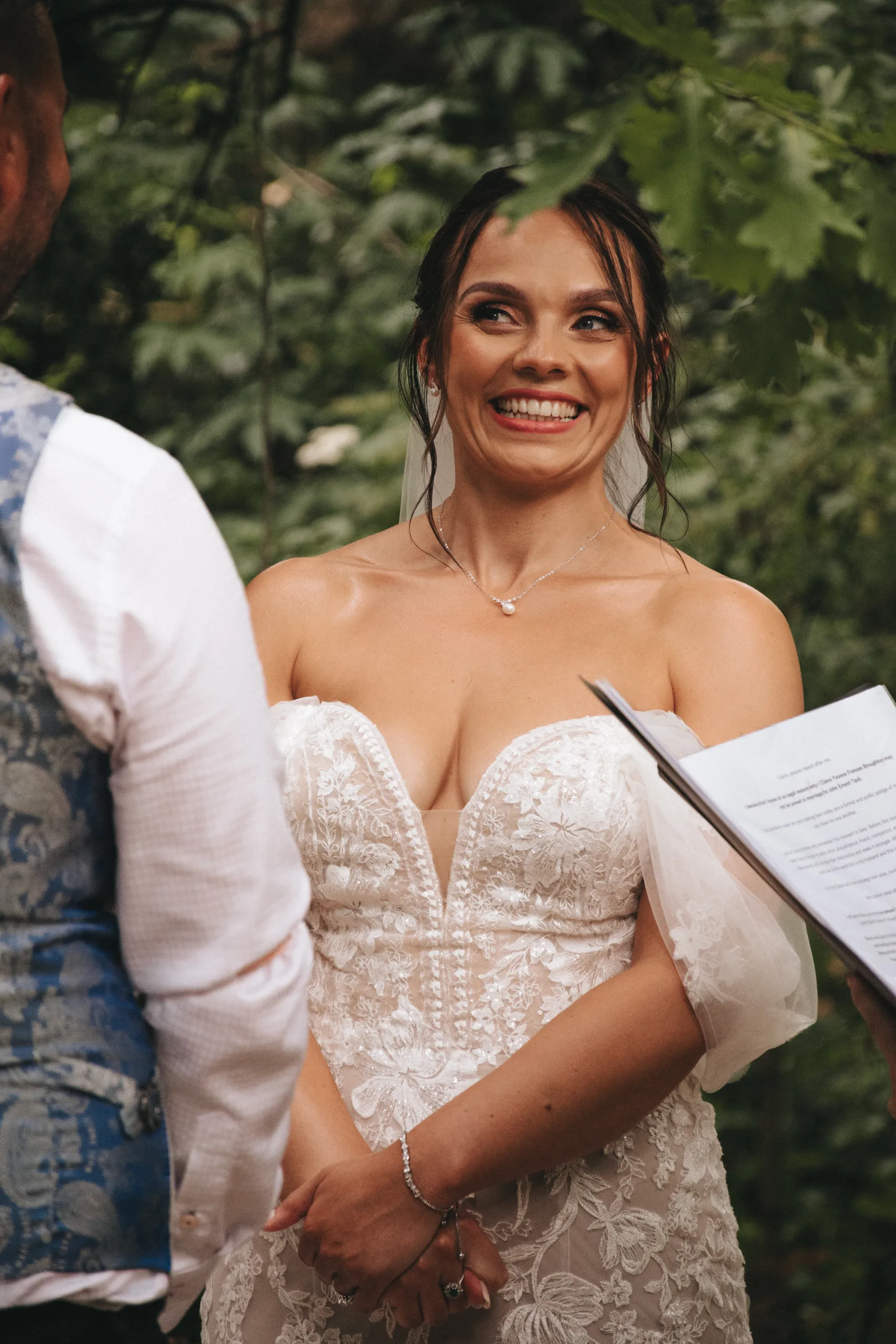A Yorkshire bride smiles as she reads her vows in the woods, captured beautifully by a photographer.