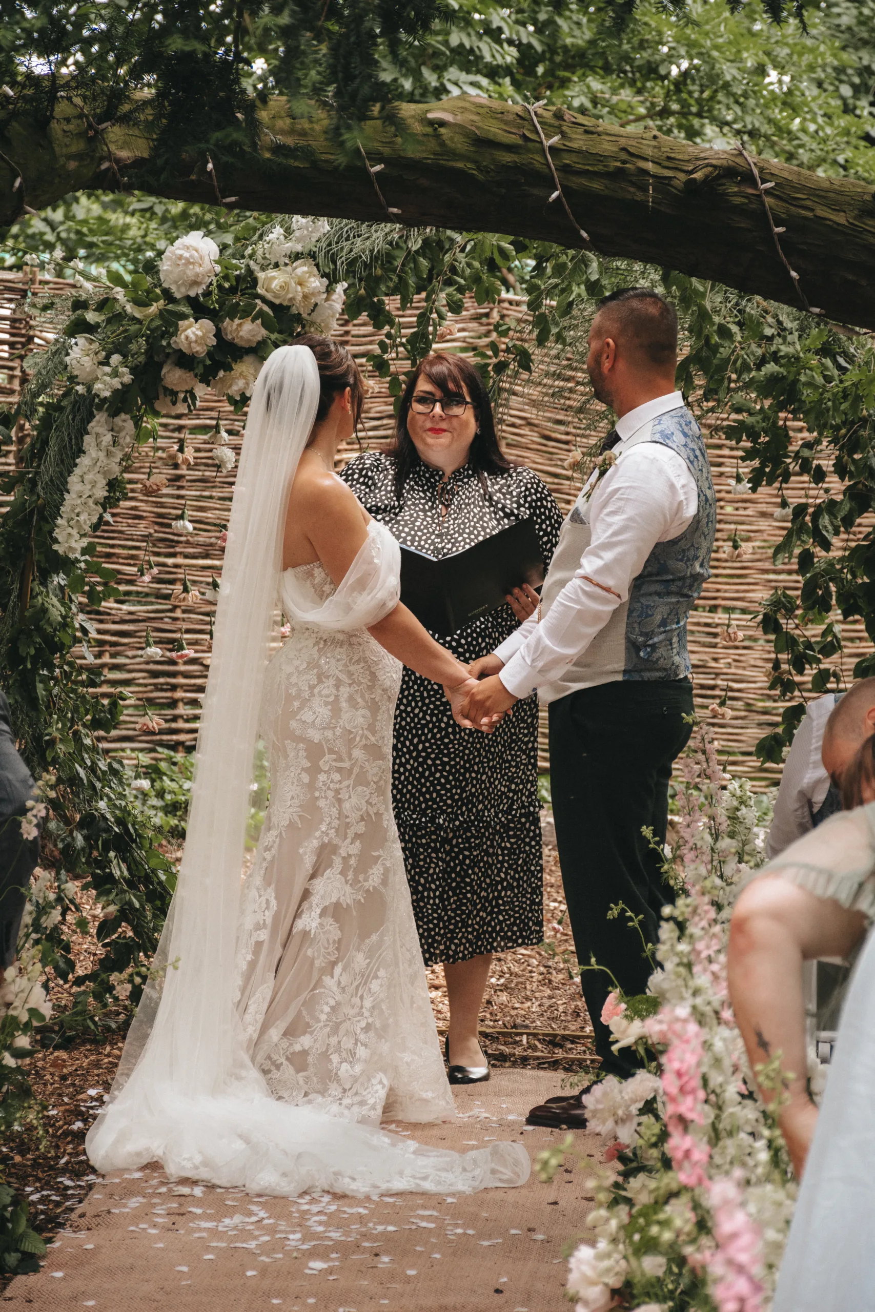 A bride and groom exchange vows under an archway in a Yorkshire garden.