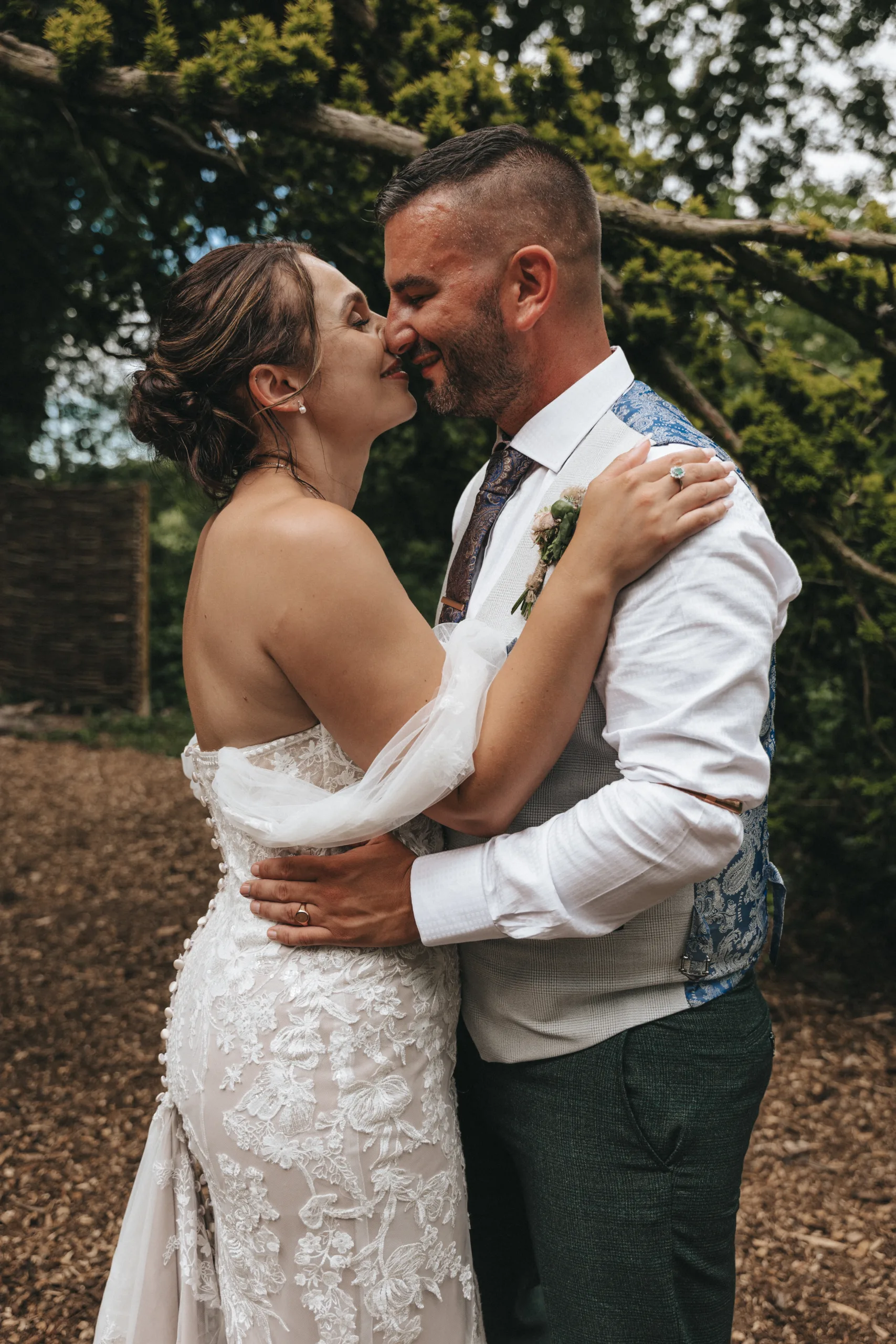 A bride and groom kissing in the woods captured in photography.