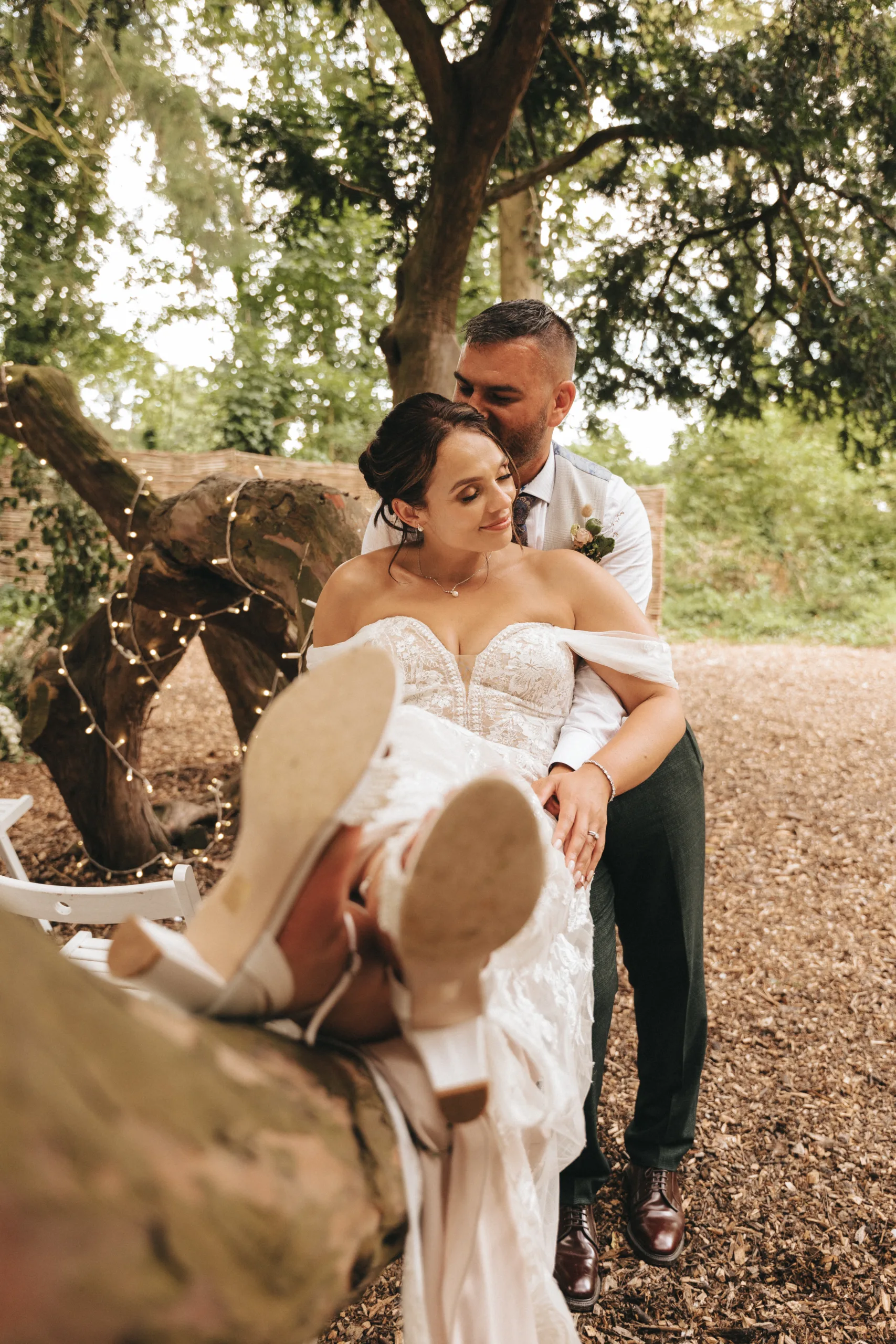 A bride and groom sitting on a log in the woods on their wedding day.