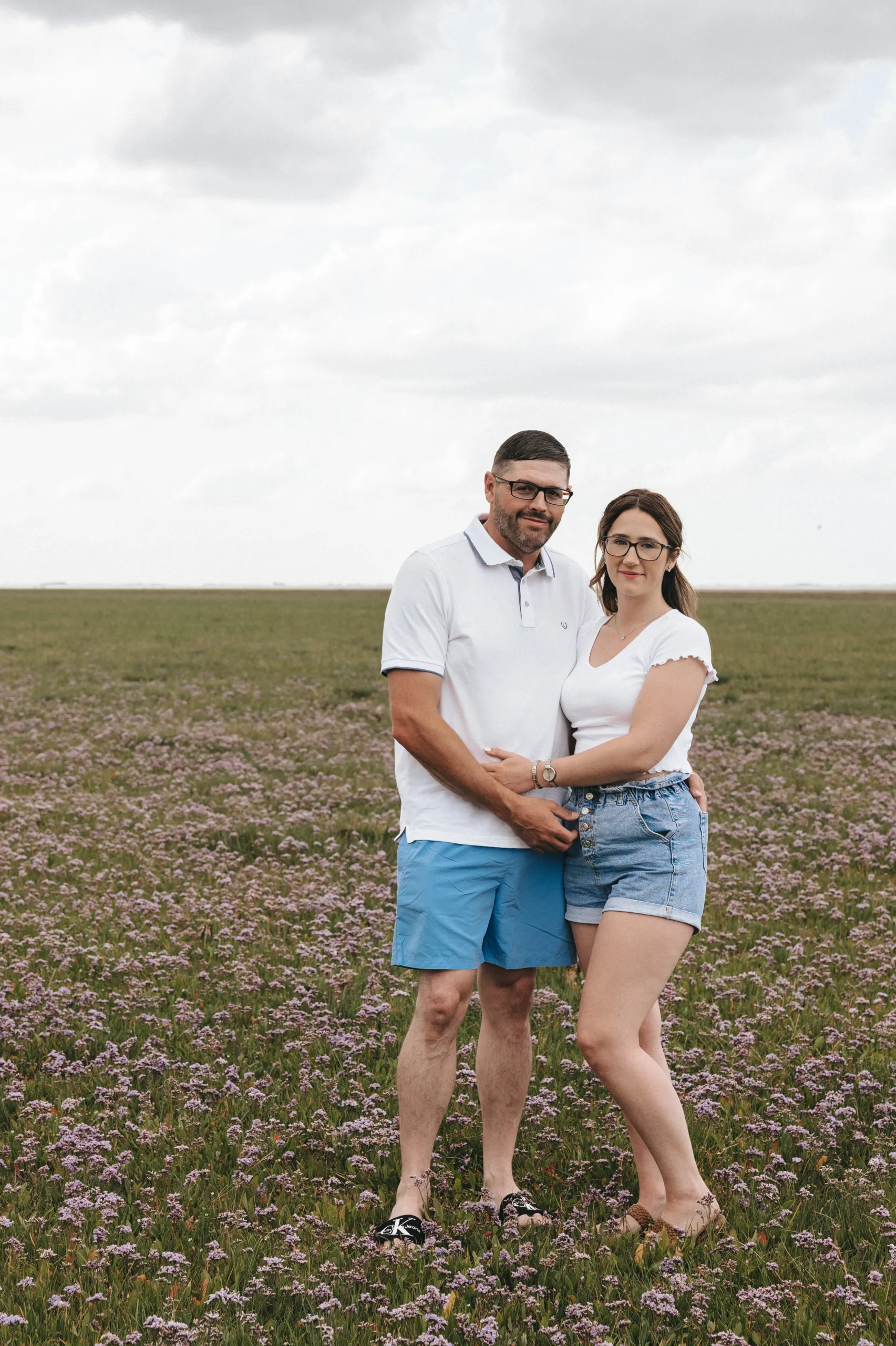 A man and woman standing in a field of purple flowers while a wedding photographer captures the moment in Lincolnshire.