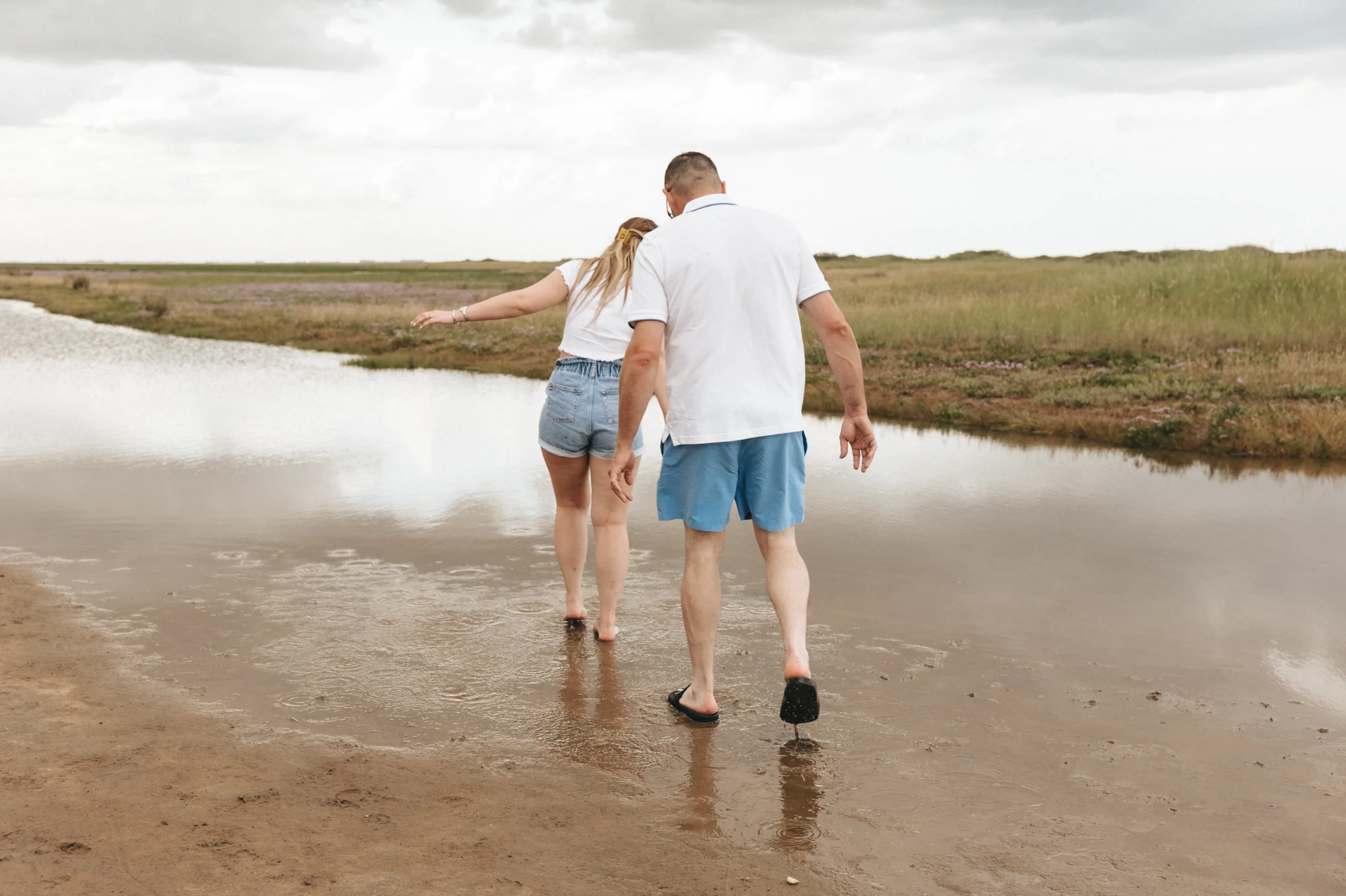 A young couple walking through a puddle on a beach captured by a Lincolnshire photographer.