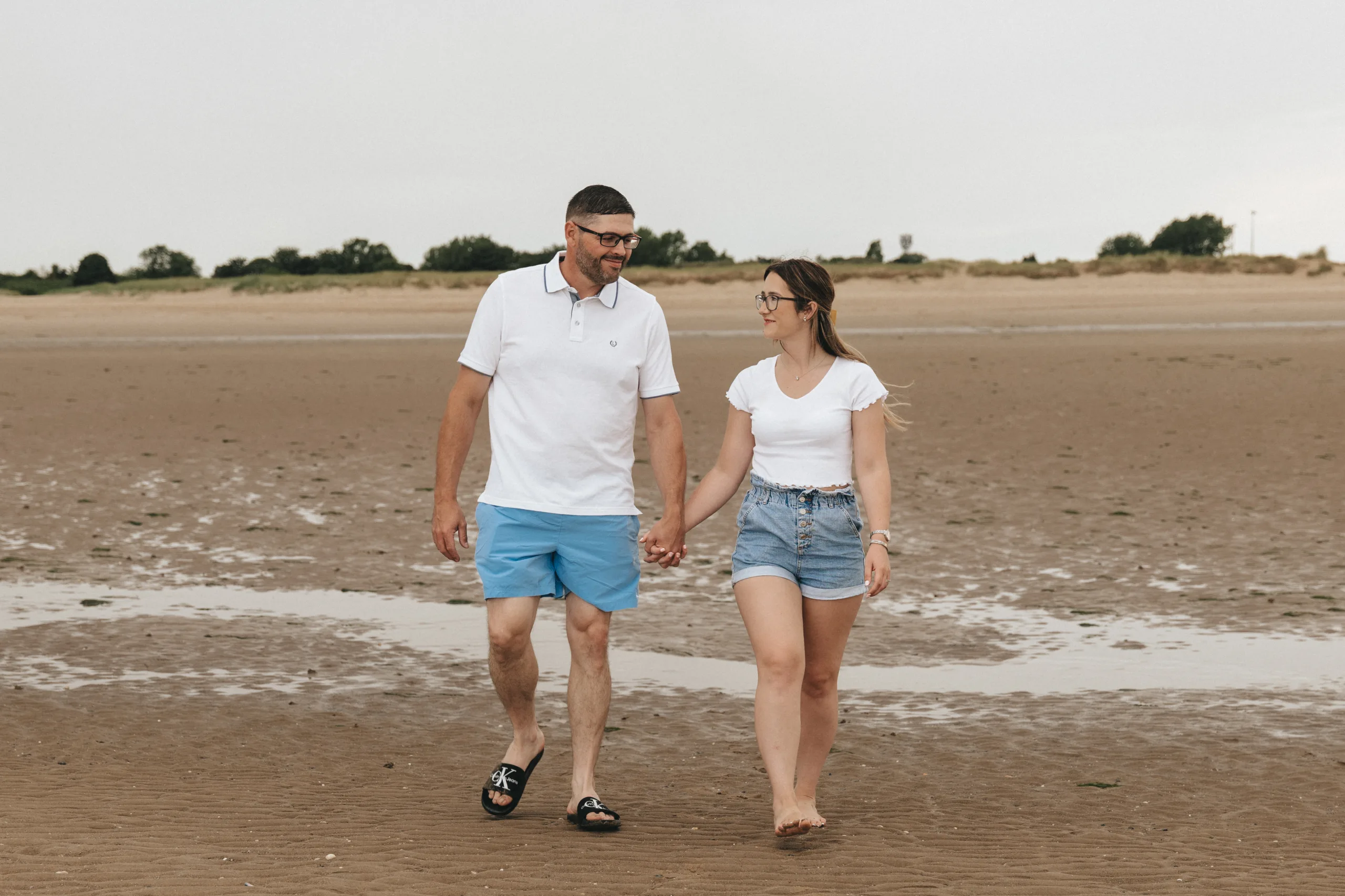 A man and woman walking on the beach holding hands in Yorkshire.