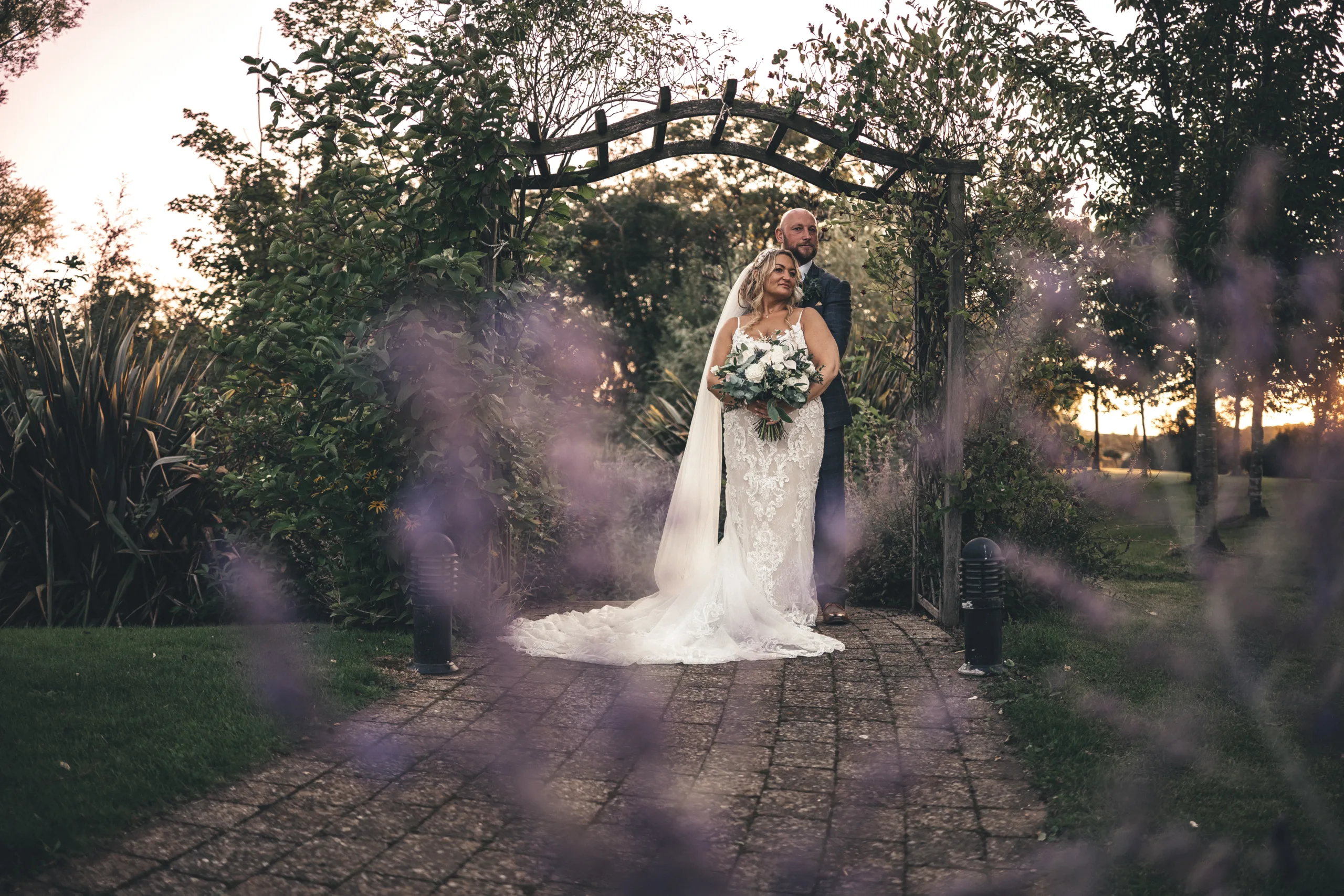 A bride and groom posing under an archway in a garden, captured by a Yorkshire photographer.