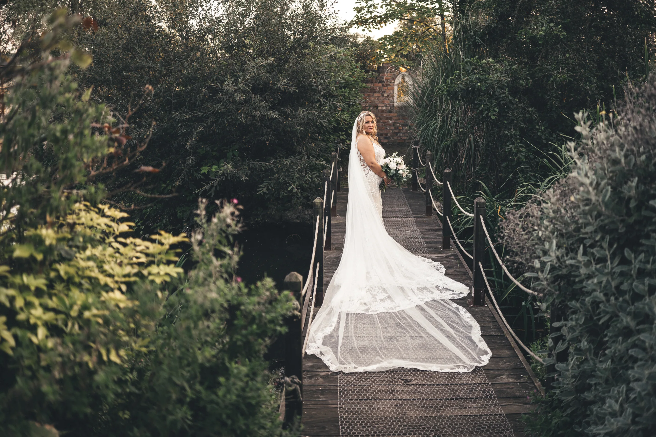 A bride standing on a wooden bridge in the woods captured by a Lincolnshire photographer.