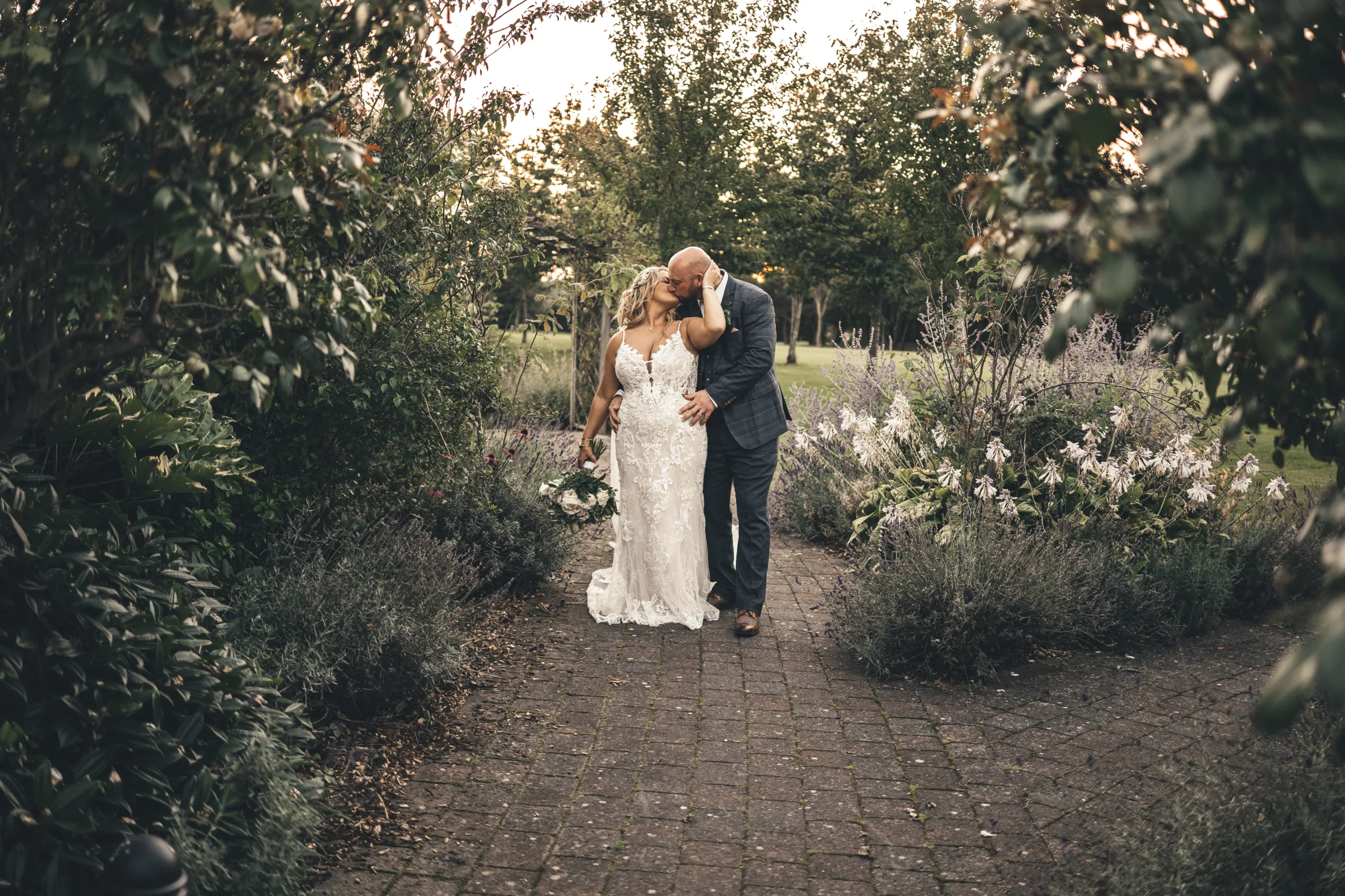 A bride and groom kissing in a garden, beautiful summer sunset wedding photography at Laceby Manor.