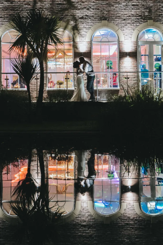 A newly married couple standing in front of a building at night after their Yorkshire wedding.