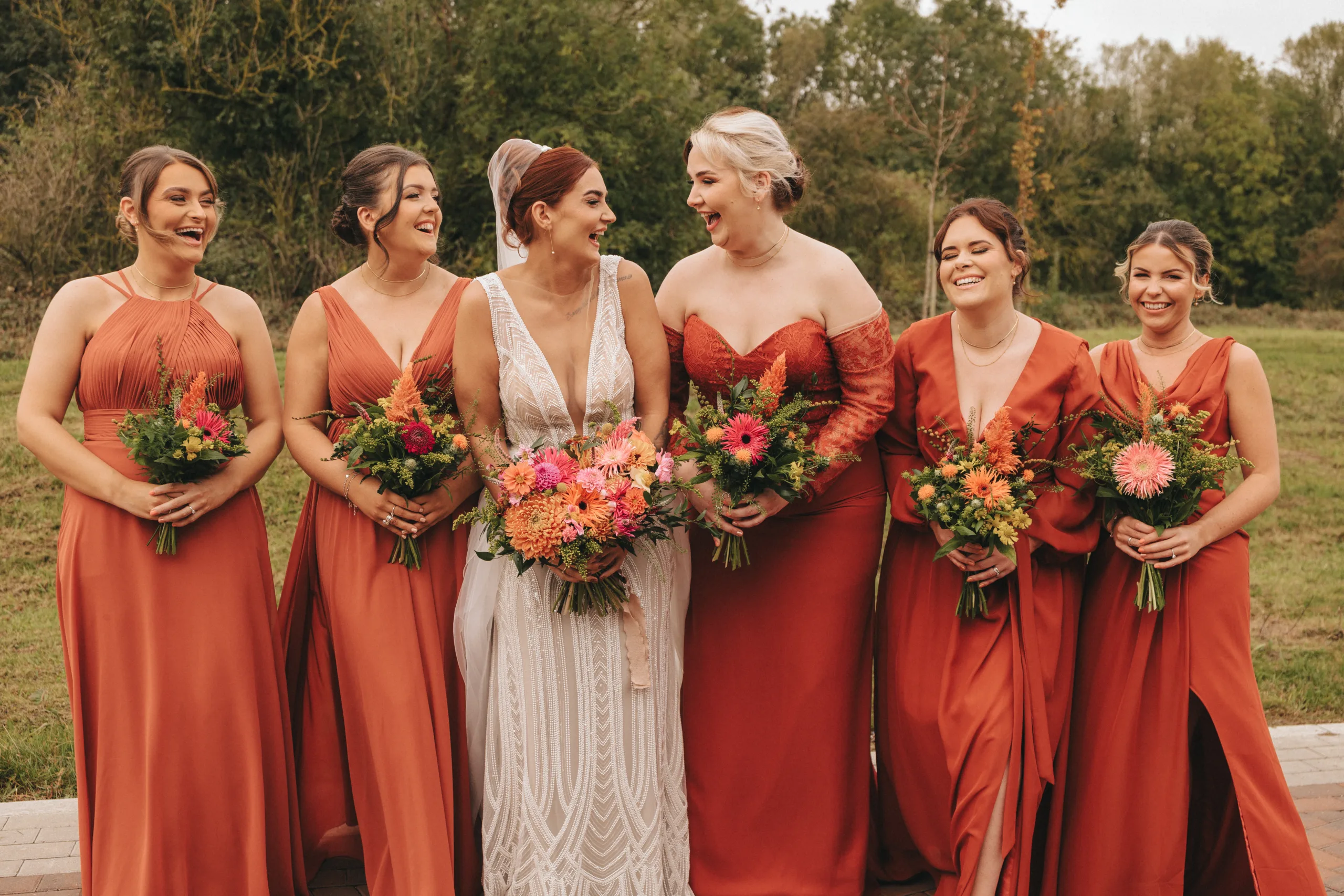 A group of bridesmaids in orange dresses pose for photographs by a Yorkshire photographer.