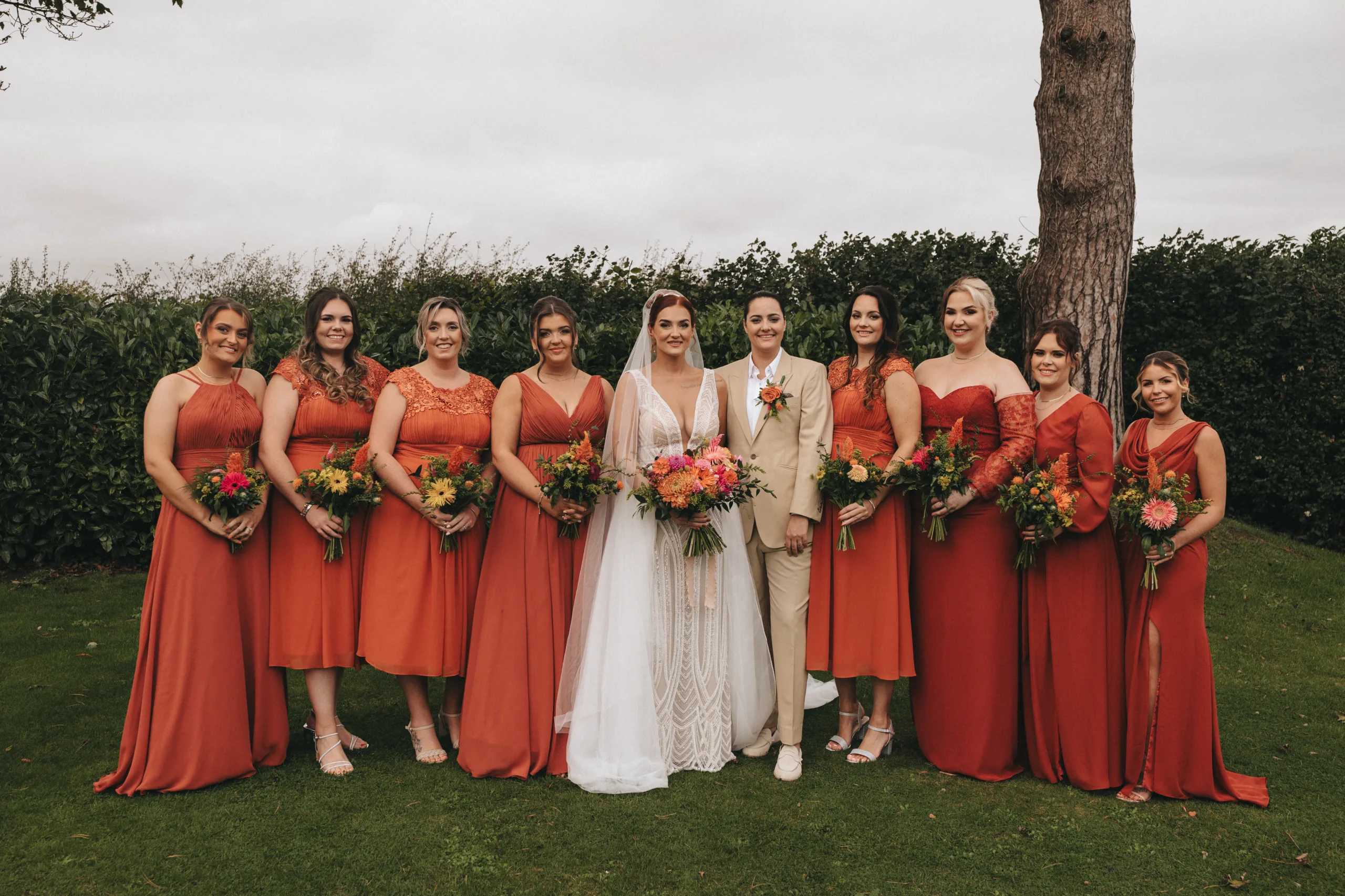 A group of bridesmaids in orange dresses posing for a wedding photo in Yorkshire.