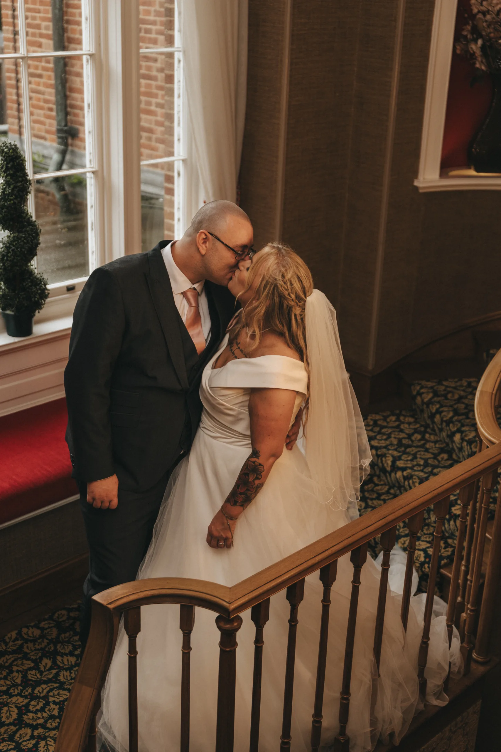 A wedding couple kissing on the stairs of a Yorkshire hotel.