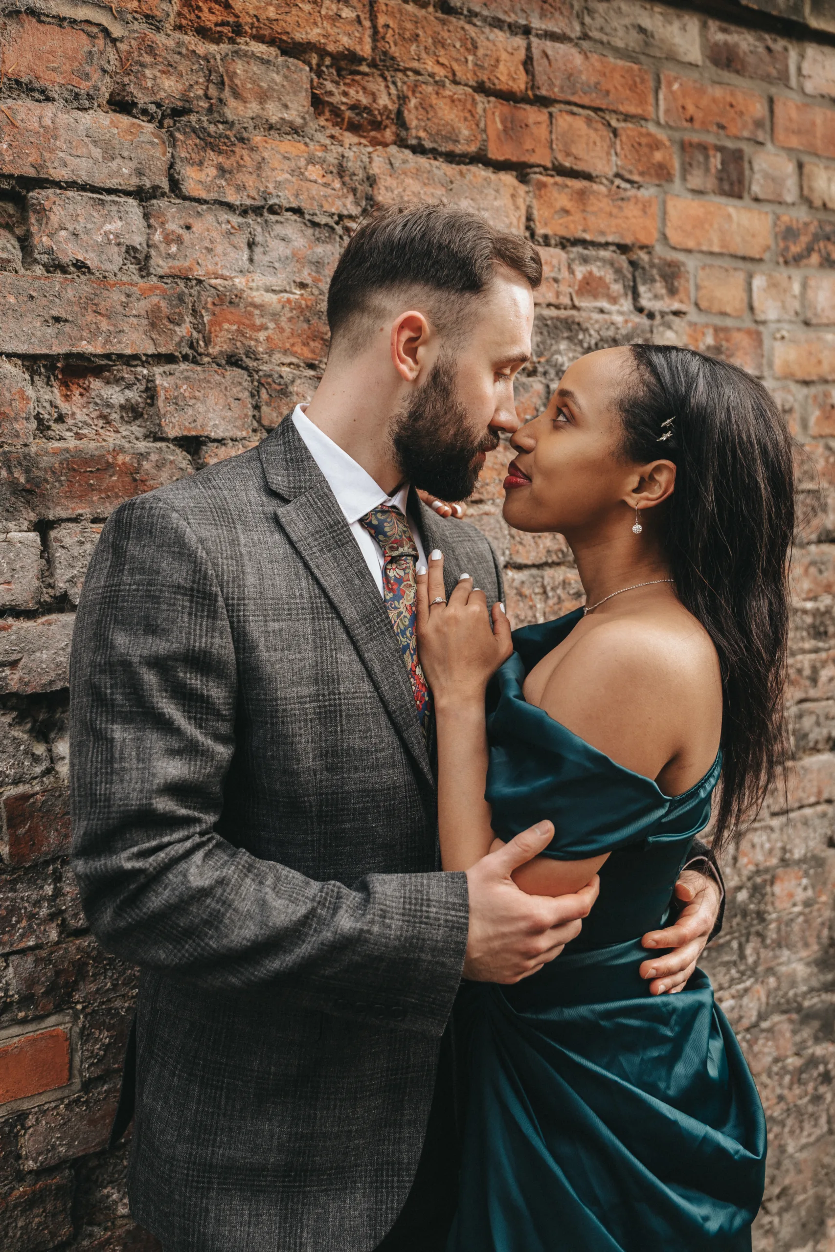 A man and woman embrace in front of a brick wall in Yorkshire.