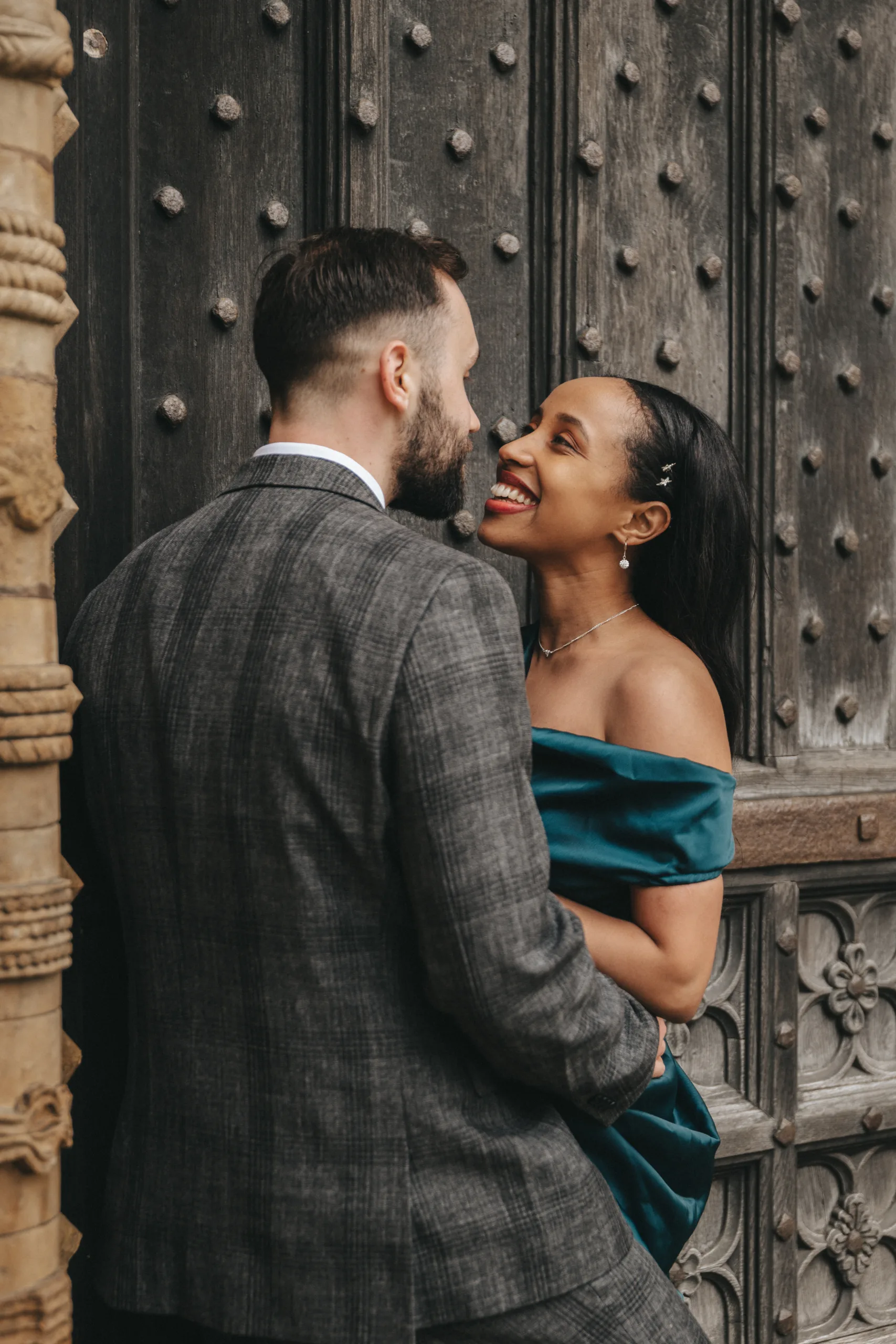 An engaged couple embracing in front of an old door, captured by a Yorkshire wedding photographer.