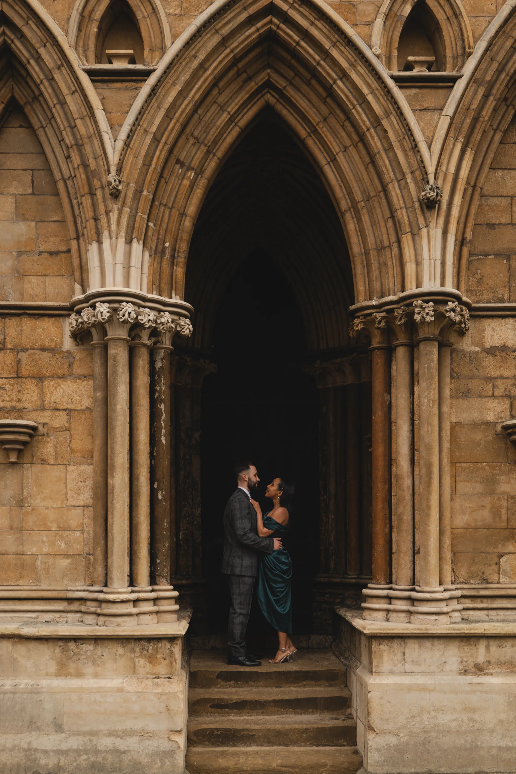 A bride and groom standing in front of an arched doorway during their Lincolnshire wedding.